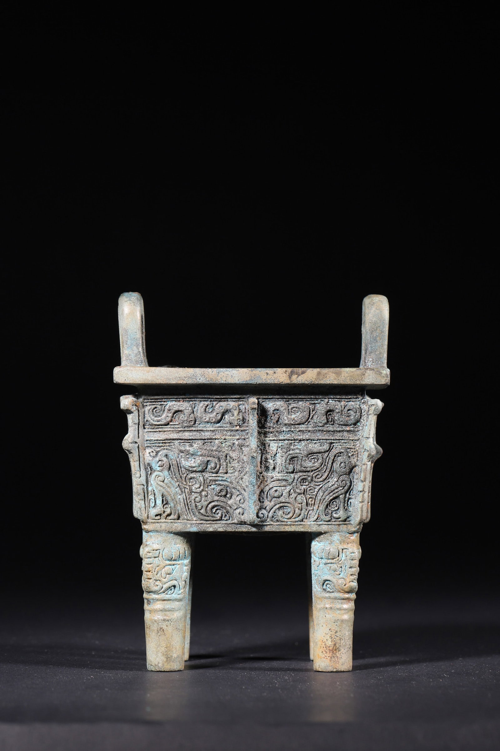 A Bronze Rectangular Ding with Taotie Motifs - Late Shang Dynasty: Length 7.5cm (2.95in), Width 6.3cm (2.48in), Height 10.5cm (4.13in), Weight 441.0g (0.97lb)This solemn ritual ding features upright ears, a square belly and four legs, decorated with intricate taotie 