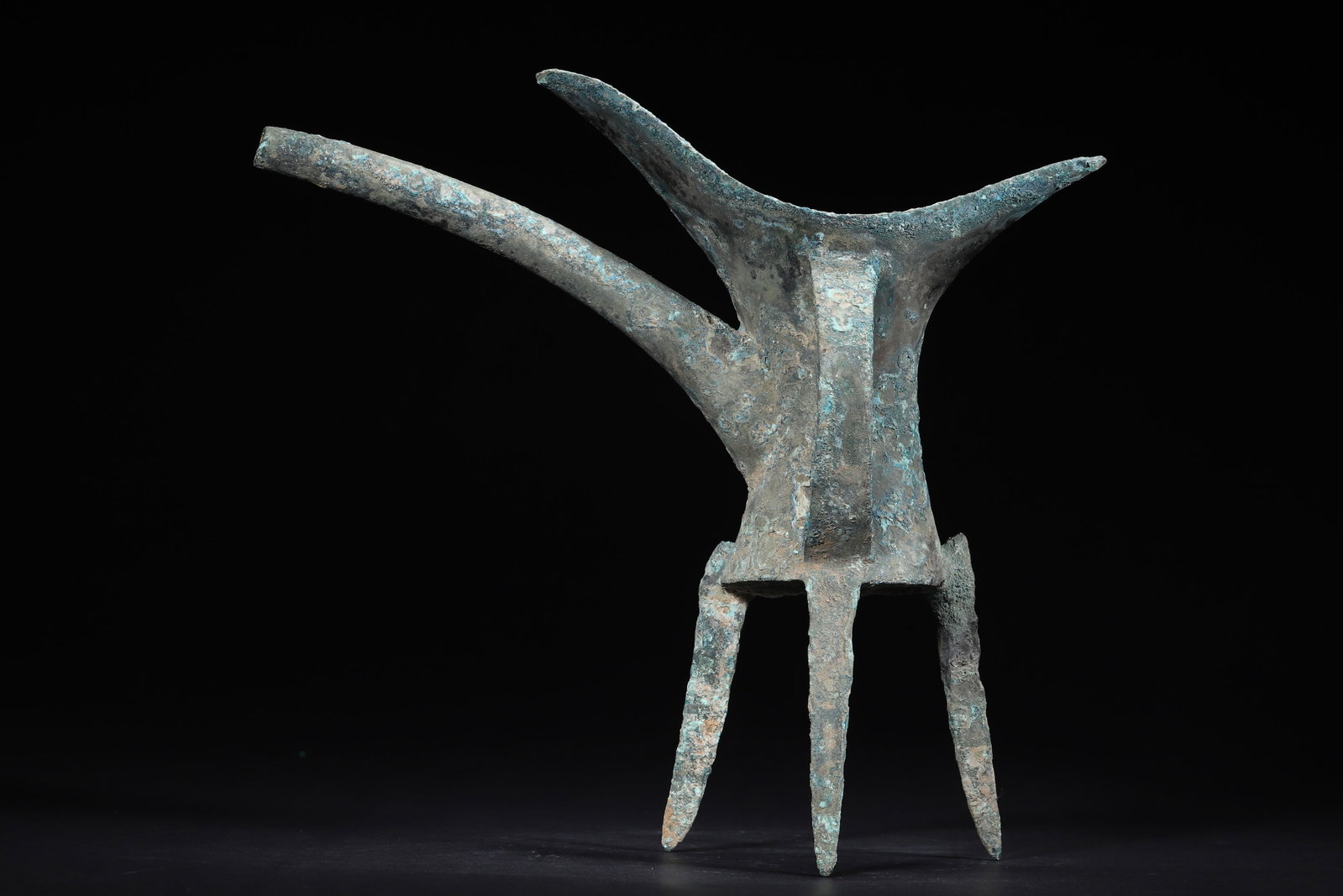 Late Shang Dynasty Bronze Plain Jue Vessel: 659.0 g (1.45 lb) | 24.0 x 18.0 x 22.0 cm (9.45 x 7.09 x 8.66 in)This Late Shang Dynasty bronze jue features a tall, elegant form with a long spout, flared tail, constricted waist, flat base, stable t