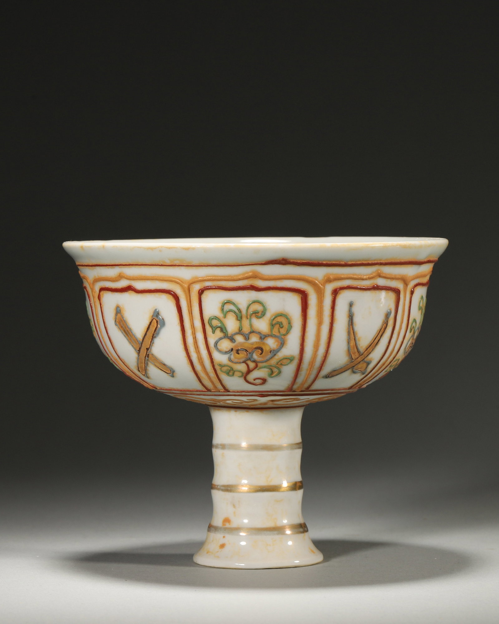 A Lifen Gold-Painted Stem Cup with Eight Auspicious Symbols, Yuan Dynasty: D 13cm (5.12 in); H 10.5cm (4.13 in)A Yuan Dynasty stem cup decorated with the "Lifen" technique, featuring raised outlines filled with polychrome and gold for the Eight Auspicious Symbols. With flora