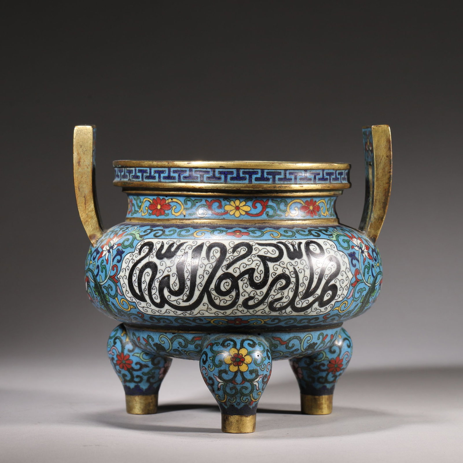 A Cloisonné Enamel Tripod Censer with Arabic Inscriptions, Marked "Made in Qianlong Period??, Qing: H 15.2cm (5.98 in); ED 16cm (6.3 in); Wt 1645g (3.63 lb)A gilt bronze cloisonné enamel tripod censer, decorated with scrolling lotus and Arabic inscriptions on a turquoise ground, with upright gilt h