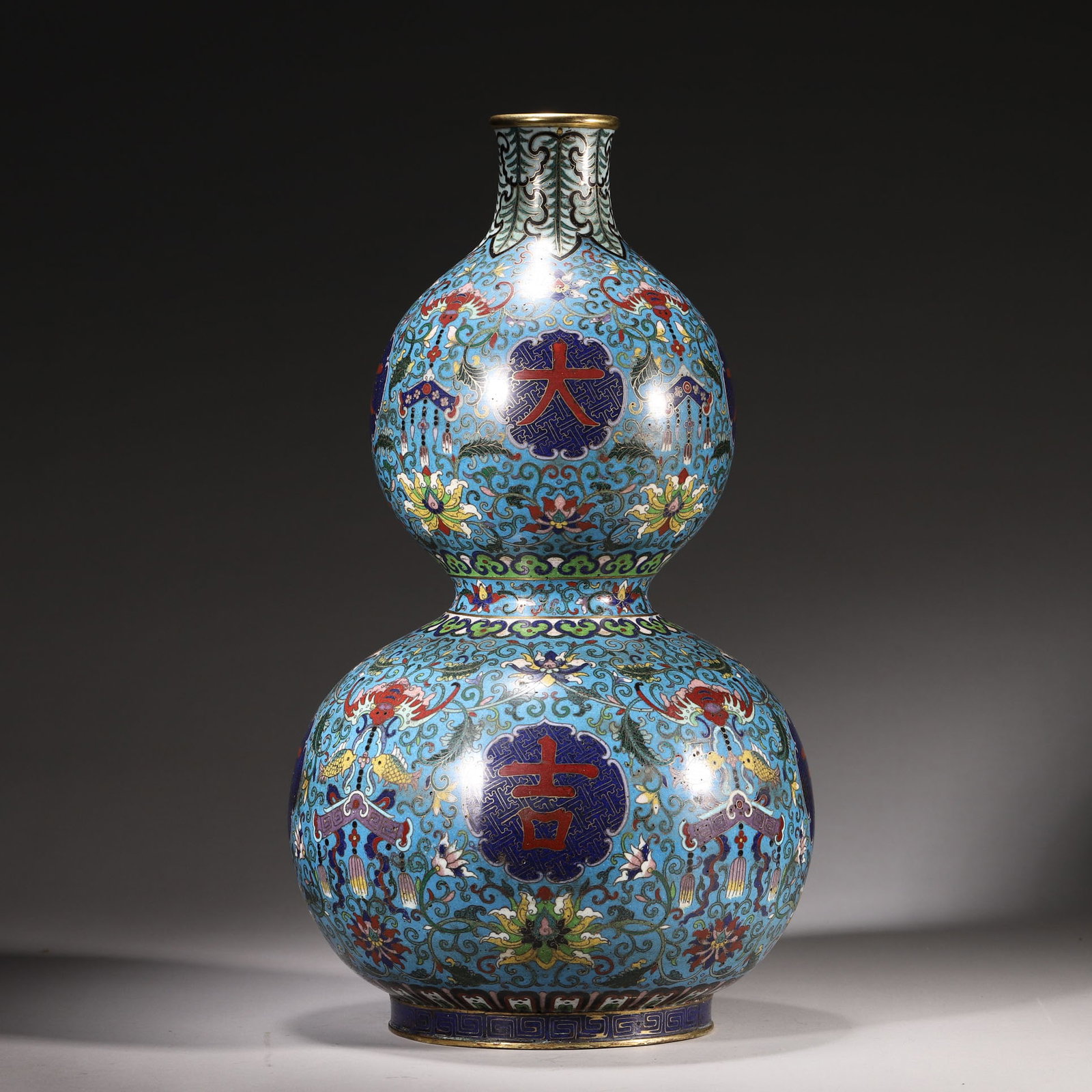 A Cloisonné Enamel "Great Auspicious?? Gourd Vase, Marked "Made in Qianlong Period??, Qing: D 20cm (7.87 in); H 37cm (14.57 in); Wt 2271g (5.01 lb)A gilt bronze cloisonné enamel gourd vase, with a turquoise ground decorated with scrolling lotus, bats and fish motifs, and "Da Ji” chara