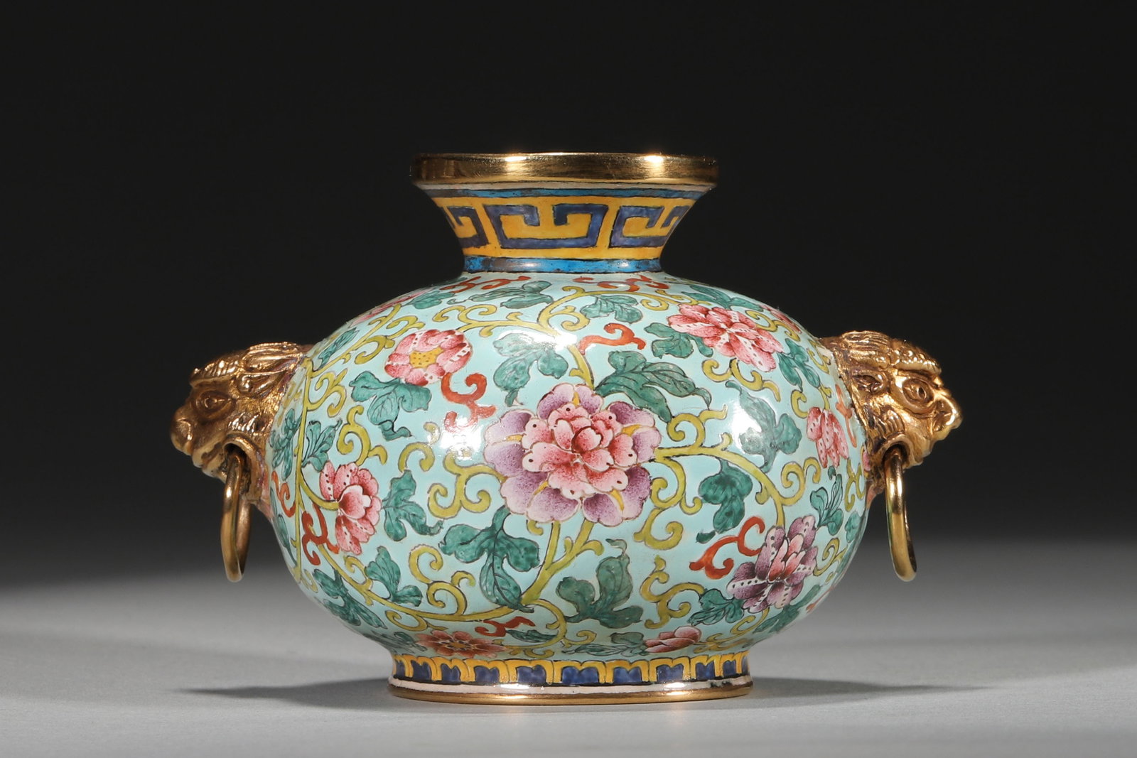 An Enamel Copper Vase With Floral Pattern And Beast Ears, Qianlong Period: 9.0cm x 6.0cm,141.0g (3.54in x 2.36in,WT 0.3109lb)With copper body and turquoise green glaze ground, it is delicately painted with interlocking flowers and decorated with gilt beast head rings. Bright