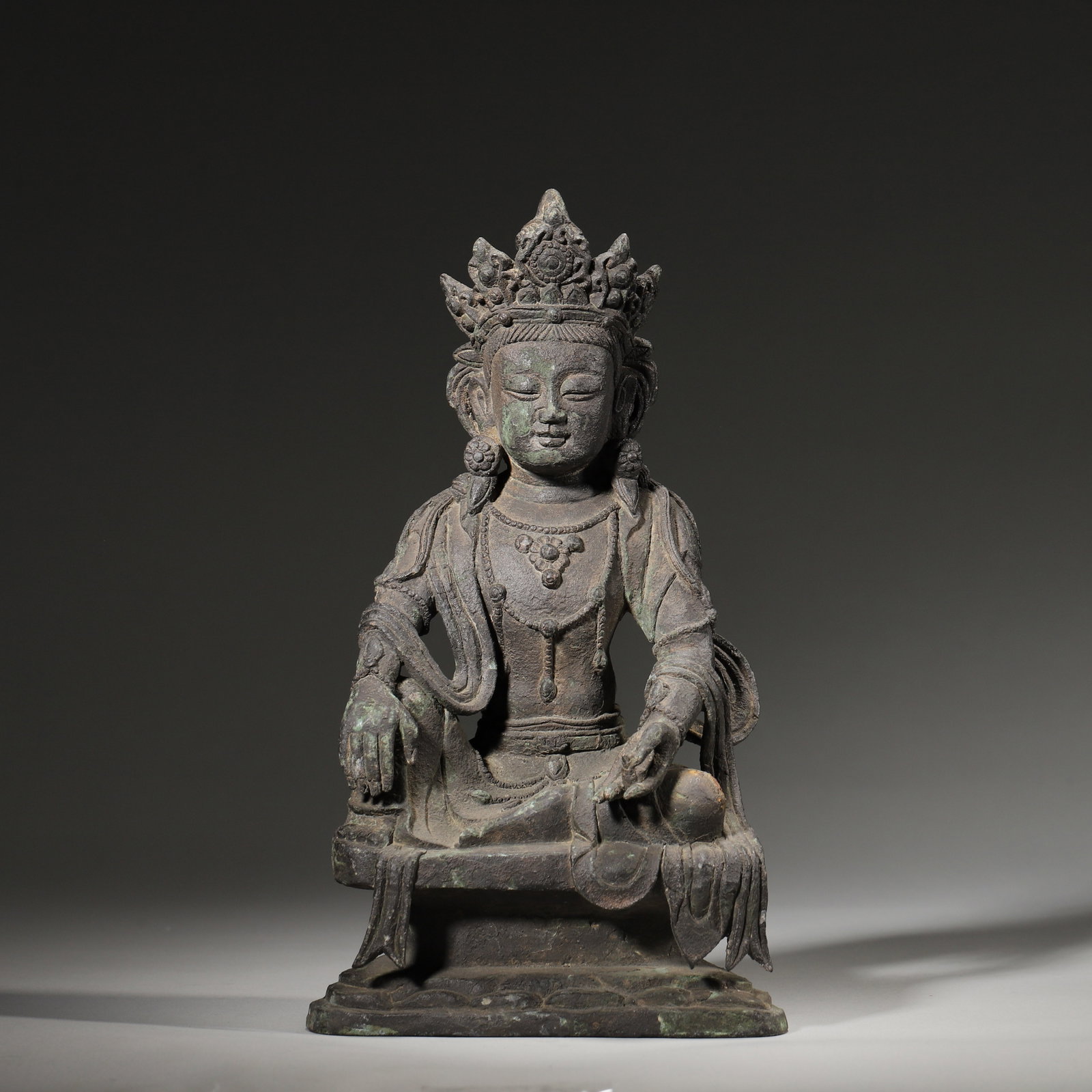 A Bronze Seated Guanyin Statue, Ming Dynasty: L 14cm (5.51 in); W 9cm (3.54 in); H 24cm (9.45 in); Wt 1879g (4.14 lb)A Ming Dynasty bronze seated Guanyin statue, wearing an ornate crown and beaded jewelry, seated in the "royal ease" posture with 