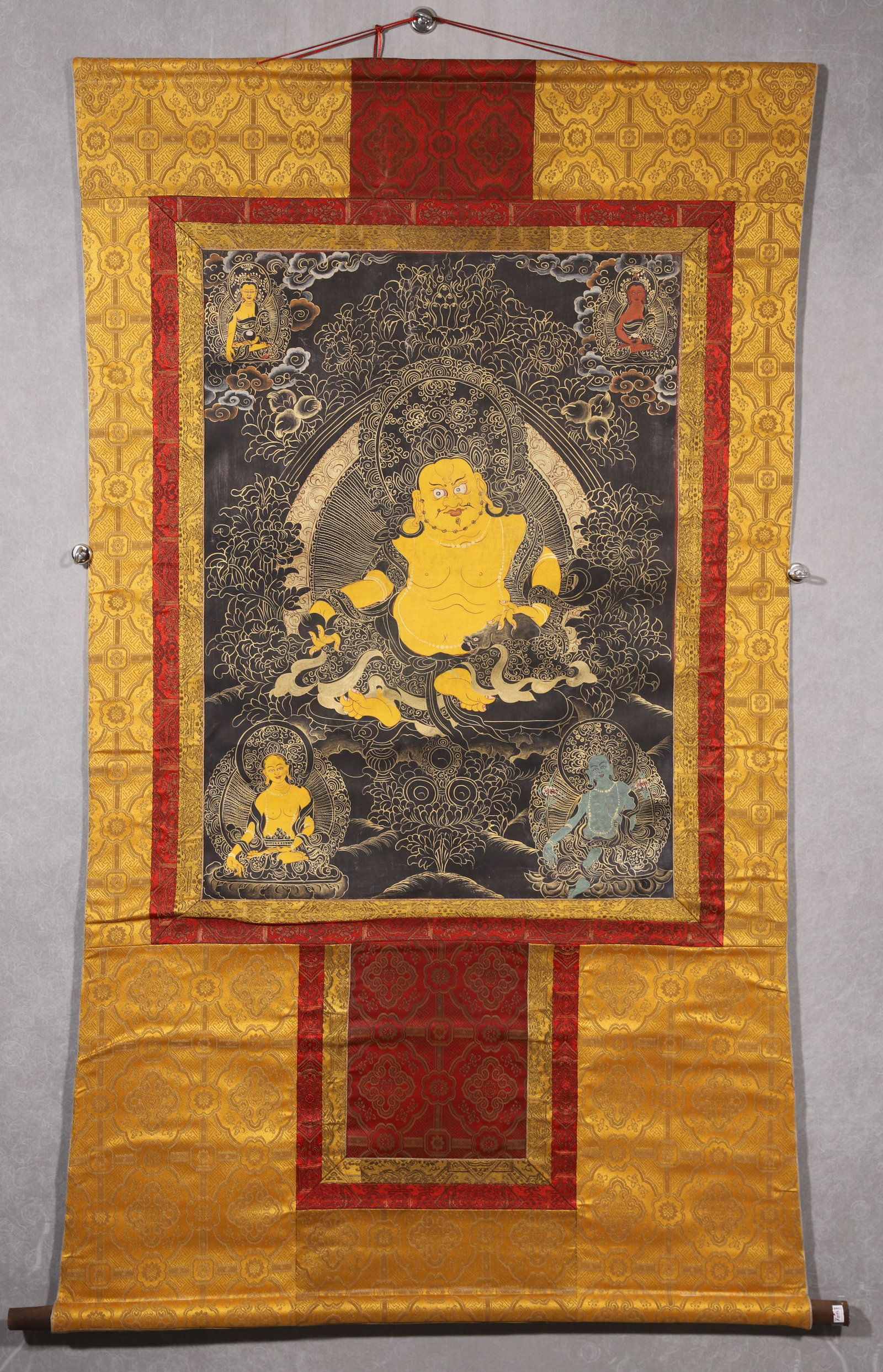 A Yellow Jambhala Black-background Thangka - Qing Dynasty: Length 78.0cm (30.71in), Width 58.0cm (22.83in)This Qing Dynasty thangka depicts Yellow Jambhala in black-background style, painted with mineral pigments and gold on cotton. The wealth deity sits sere