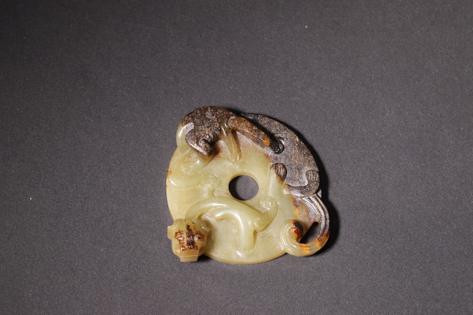 A Hetian Jade Chi Dragon Bi-Shaped Pendant - Han Dynasty: Length 5.5cm (2.17in), Width 5.5cm (2.17in), Weight 31.0g (0.07lb)This Han Dynasty pendant is finely carved from Hetian jade with natural aged patina. It features a relief-carved chi dragon on the fro