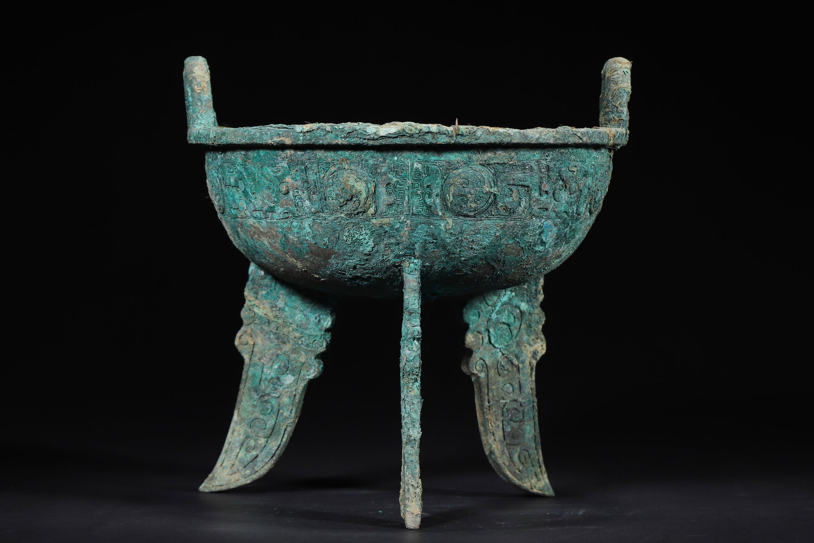 Late Shang Dynasty Bronze Ding with Taotie Pattern and Flat Feet: 1283.0 g (2.83 lb) | D 19.0 cm (D 7.48 in)This Late Shang Dynasty bronze ding features a powerful form with upright ears, flared mouth, curved belly and three flat feet, full of tension. The body is f
