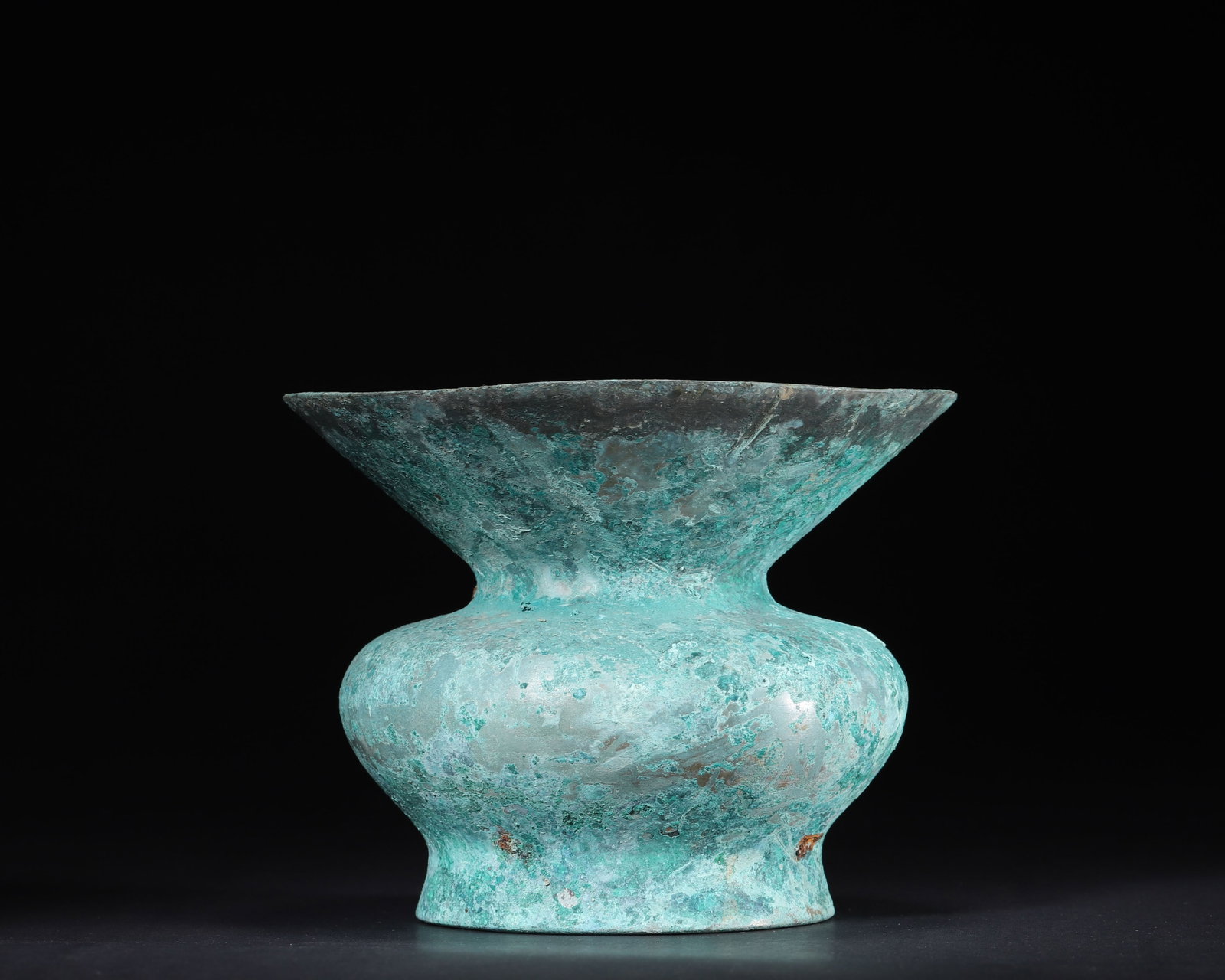 A Han Dynasty Plain Bronze Zun Vessel: 956.0 g (2.11 lb) | D 15.0 cm (D 5.91 in)This Han Dynasty plain bronze zun vessel features an elegant, expansive form with a flared mouth, constricted neck, bulging body and foot ring, boasting smooth
