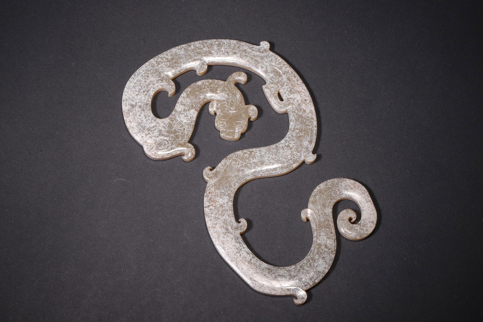 An Ancient Jade S-Shaped Dragon Pendant - Han Dynasty: Length 13.0cm (5.12in), Width 8.0cm (3.15in), Weight 73.0g (0.16lb)This S-shaped dragon pendant is elaborately carved from ancient jade, featuring a coiled dragon with smooth flowing lines. With natur