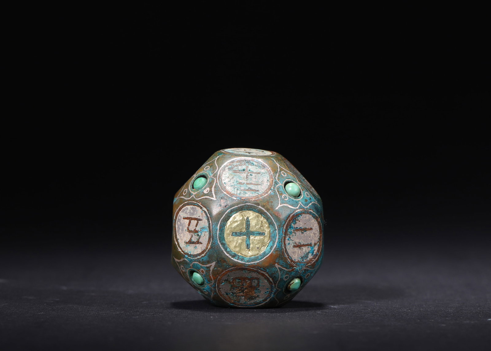 A Bronze Dice with Gold and Silver Inlay and Turquoise, Han Dynasty: D 4cm (1.57 in); Wt 151g (0.33 lb)This Han Dynasty multi-sided bronze dice features fine gold and silver inlay with turquoise inlays. Carved with numbers and characters, it is a rare example reflectin