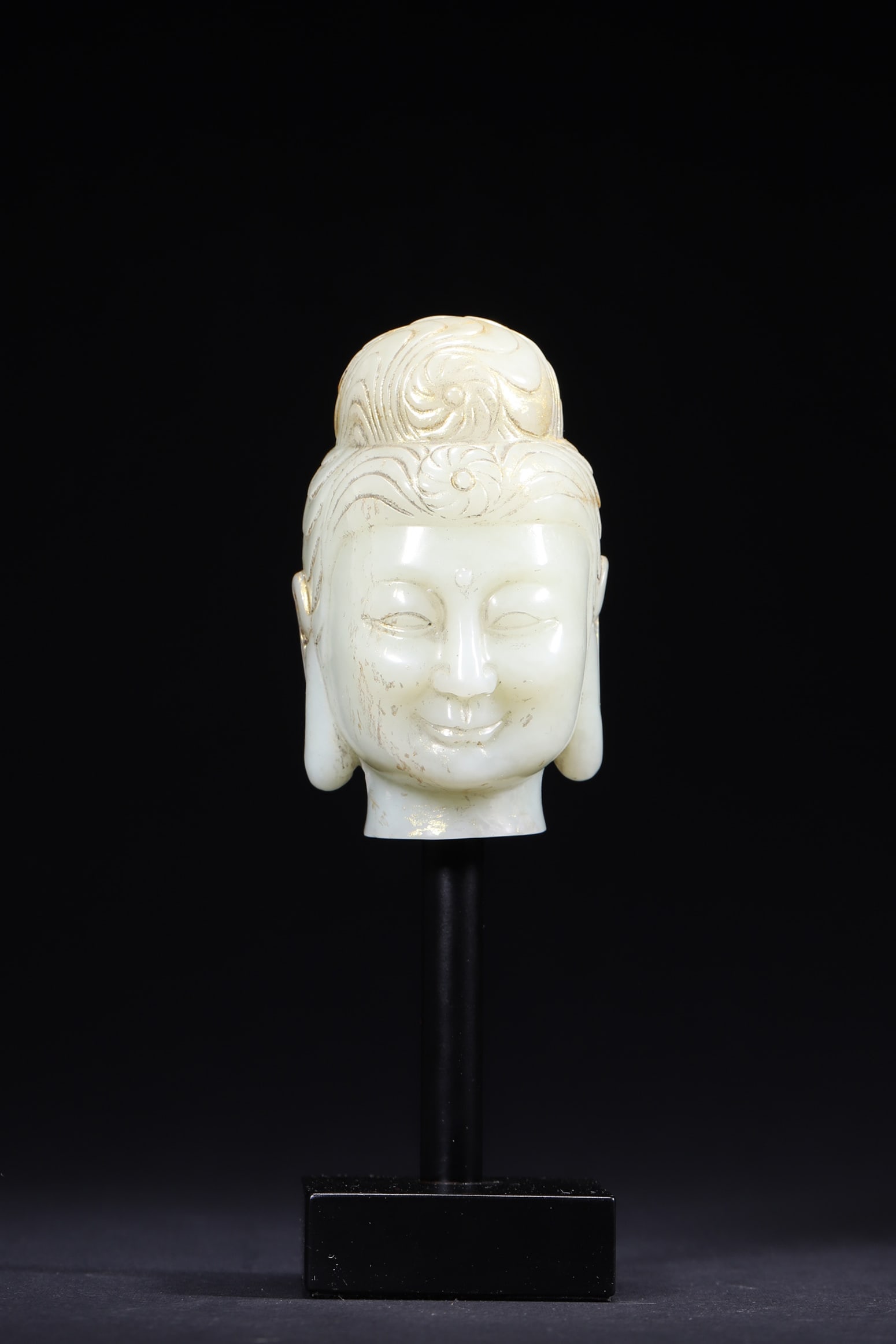 A Hetian White Jade Buddha Head with Gilded Details, Qing Dynasty: Length 5.1cm (2.01in), Width 5.5cm (2.17in), Height 8.5cm (3.35in), Weight 343.0g (0.76lb)This is a Qing Dynasty Hetian white jade Buddha head with gilded details. Carved with serene features and gild