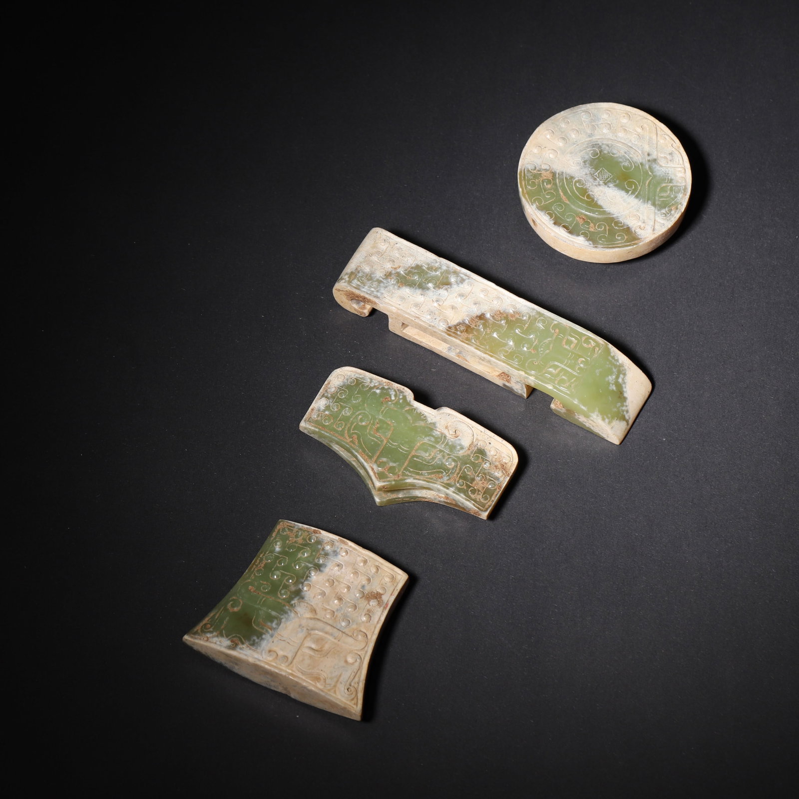 A Set of Hetian Celadon Jade Sword Fittings, Han Dynasty: L 10cm (3.94 in); W 2.3cm (0.91 in); Wt 259g (0.57 lb)A complete set of Han Dynasty Hetian celadon jade sword fittings, including pommel, guard, slide, and chape. Decorated with cloud and beast patter