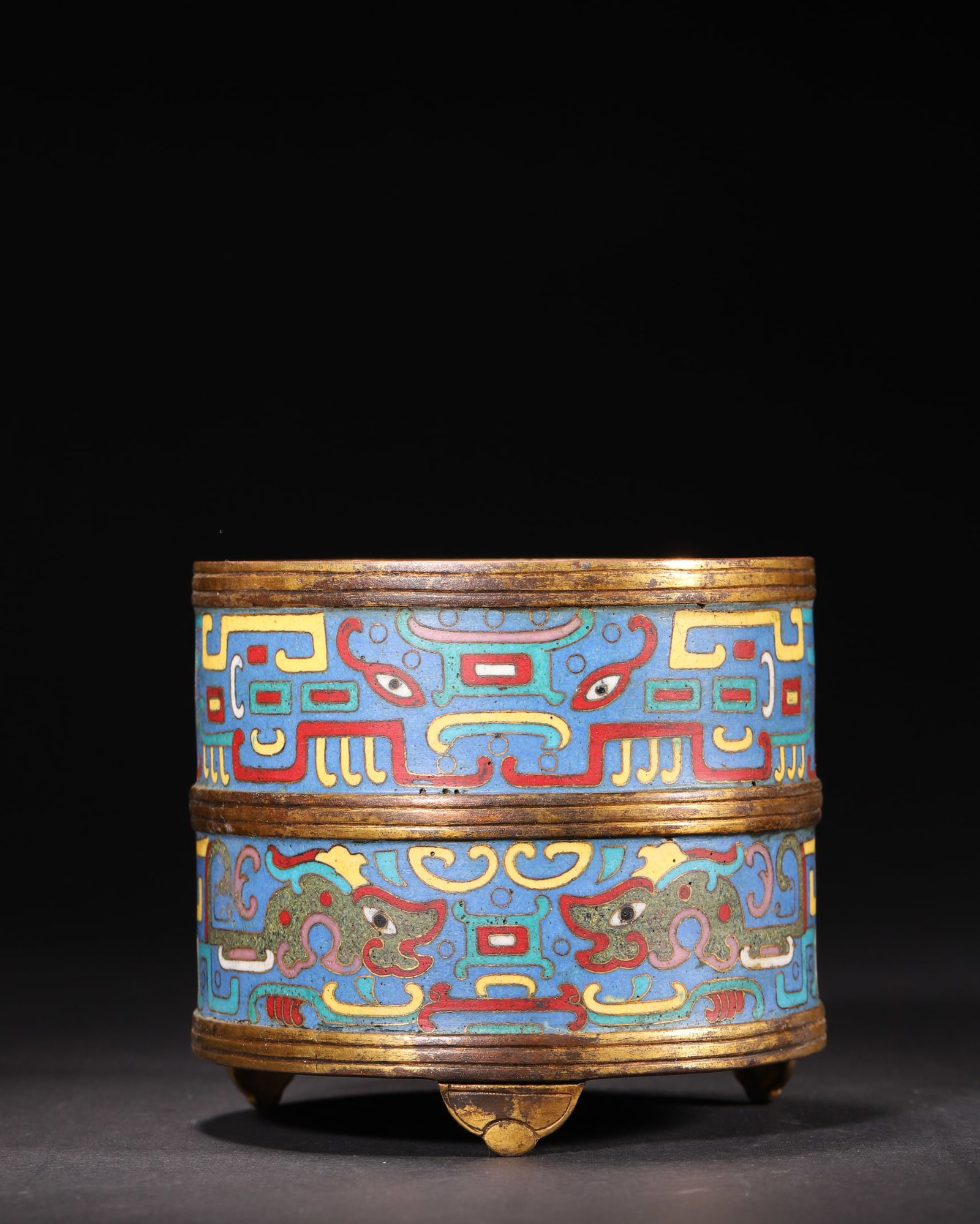A Gilt-Bronze Cloisonné Enamel Tripod Censer with Archaistic Beast Mask Design, Qianlong Period,: Diameter 10.5cm (4.13in), Height 9.5cm (3.74in), Weight 565.0g (1.25lb)A gilt-bronze tripod censer from the Qianlong period of the Qing Dynasty, cast in a straight cylindrical form with three ruyi-sha