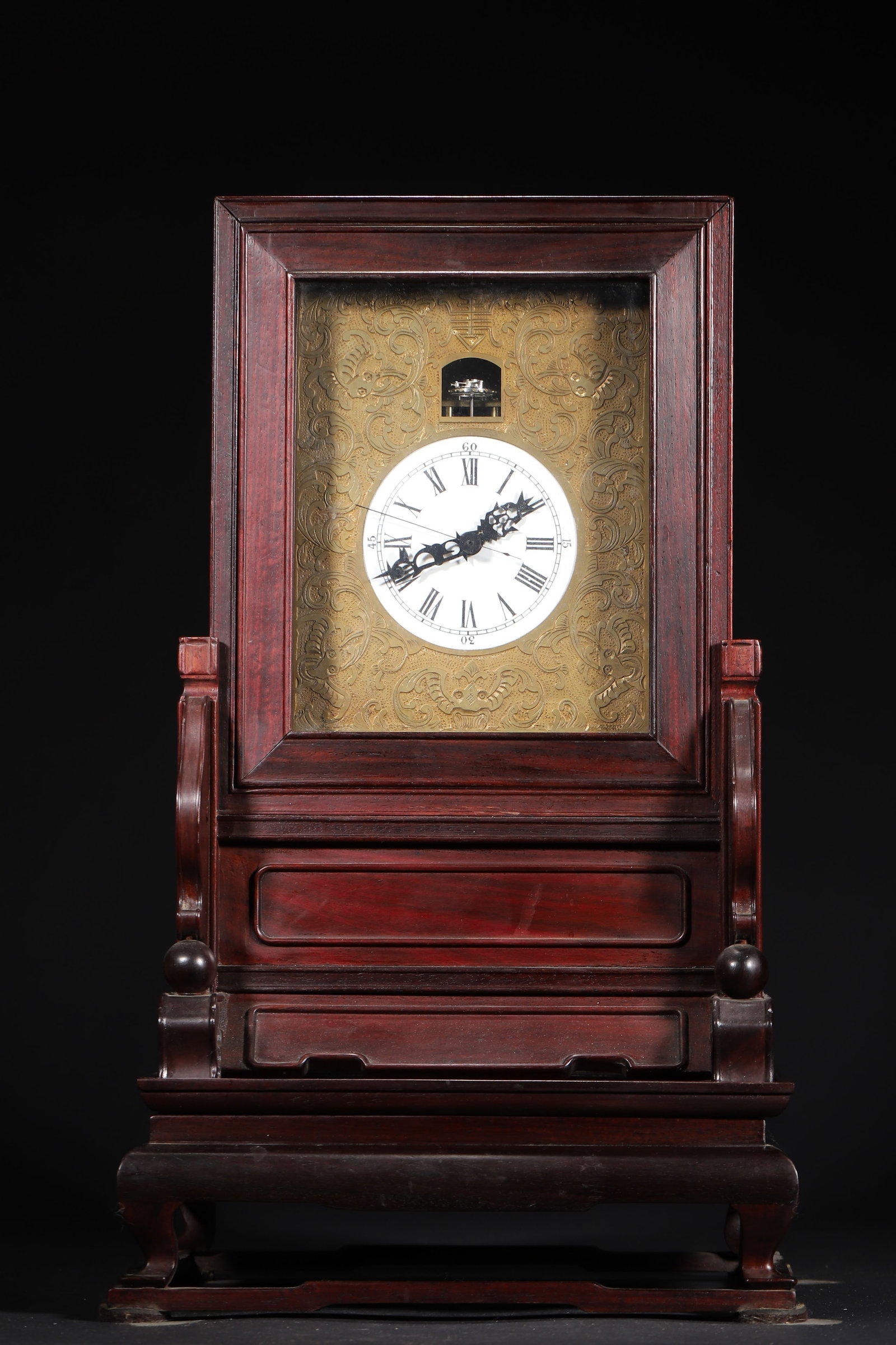 A Redwood Clock of the Qing Dynasty: 24.0cm x 21.0cm x 41.0cm,4.0kg (9.45in x 8.27in x 16.14in,WT 8.8185lb)This shelf clock is finely crafted from redwood, with an elegant form, an engraved copper backplate with bat motifs, and a white e