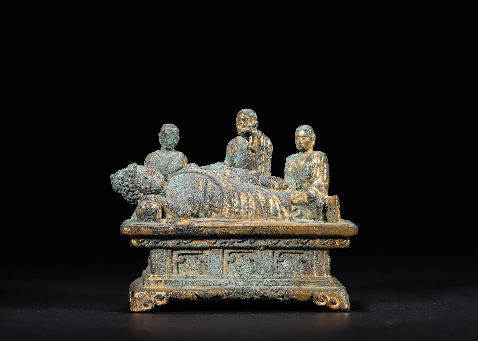 A Gilt-Bronze Statue of Sakyamuni's Nirvana, Ming Dynasty: 11.0 x 6.0 x 9.0 cm (4.33 x 2.36 x 3.54 in), WT 585.0 g (1.29 lb)A Ming gilt-bronze statue of Sakyamuni’s Nirvana shows the Buddha lying peacefully on a couch with eyes closed. Three grieving discip