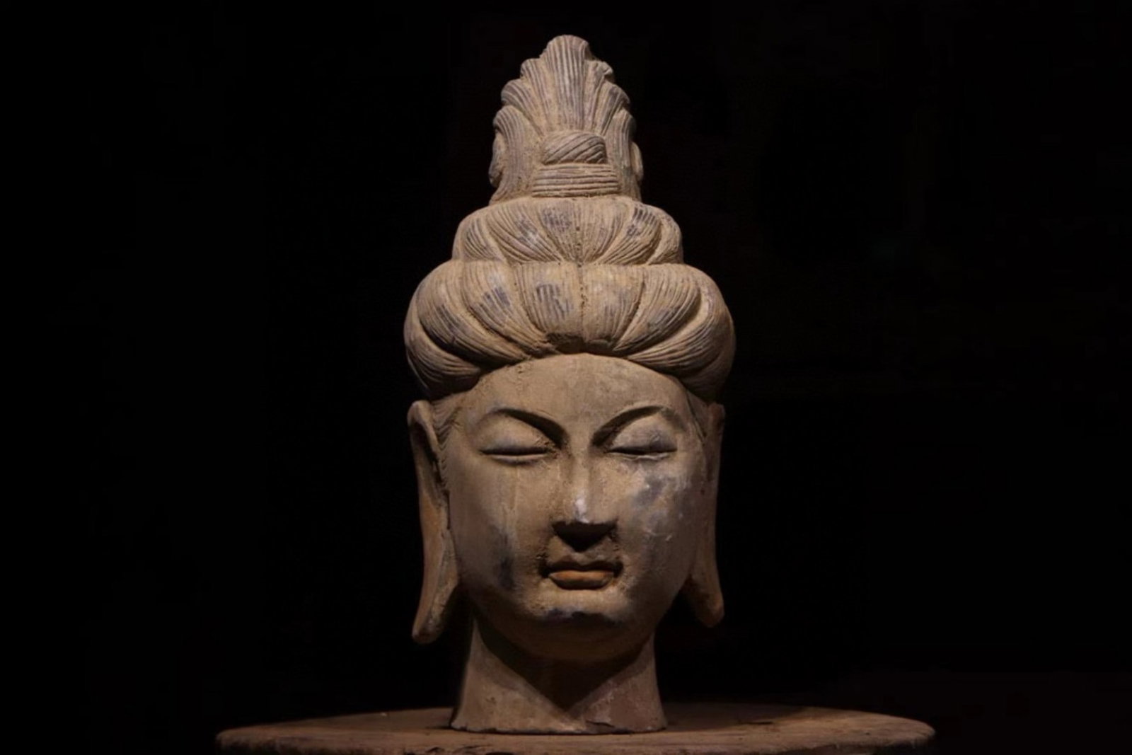 A Painted Pottery Head of Bodhisattva - Tang Dynasty: Height 38cm (14.96 in)This painted pottery head of a Bodhisattva dates to the Tang Dynasty. With an elaborate hairstyle and serene face, it reflects the elegant and refined aesthetic of Tang Buddhist 