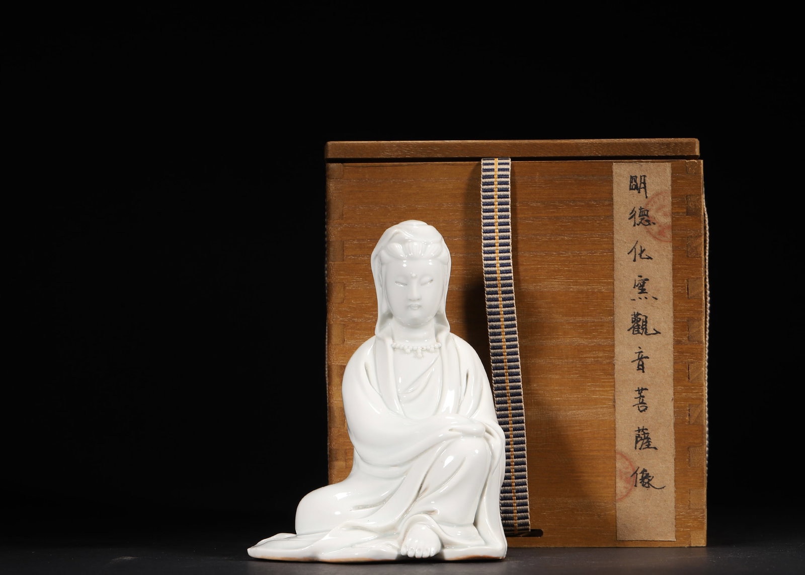 A Ming Dynasty Dehua Kiln White Glaze Seated Guanyin Statue: 9.5 x 8.0 x 13.0 cm (L x W x H = 3.74 x 3.15 x 5.12 in)This Ming Dynasty Dehua Kiln white glaze seated Guanyin statue features an elegant, serene posture with flowing, natural robe folds. The entire b