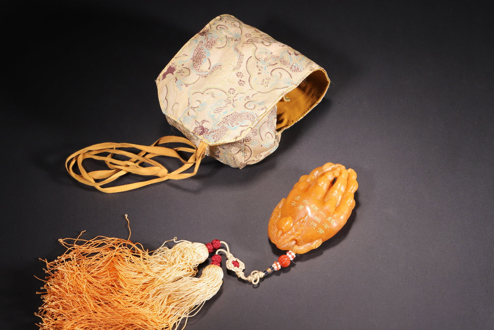 A Tianhuang Stone Buddha's Hand Ornament with Inscription, Qianlong Period, Qing Dynasty: Length 9.2cm (3.62in), Width 5.7cm (2.24in), Weight 178.0g (0.39lb)This Qianlong-period Tianhuang stone ornament is carved into a Buddha's hand with gilded inscription, embodying the superb craftsmans