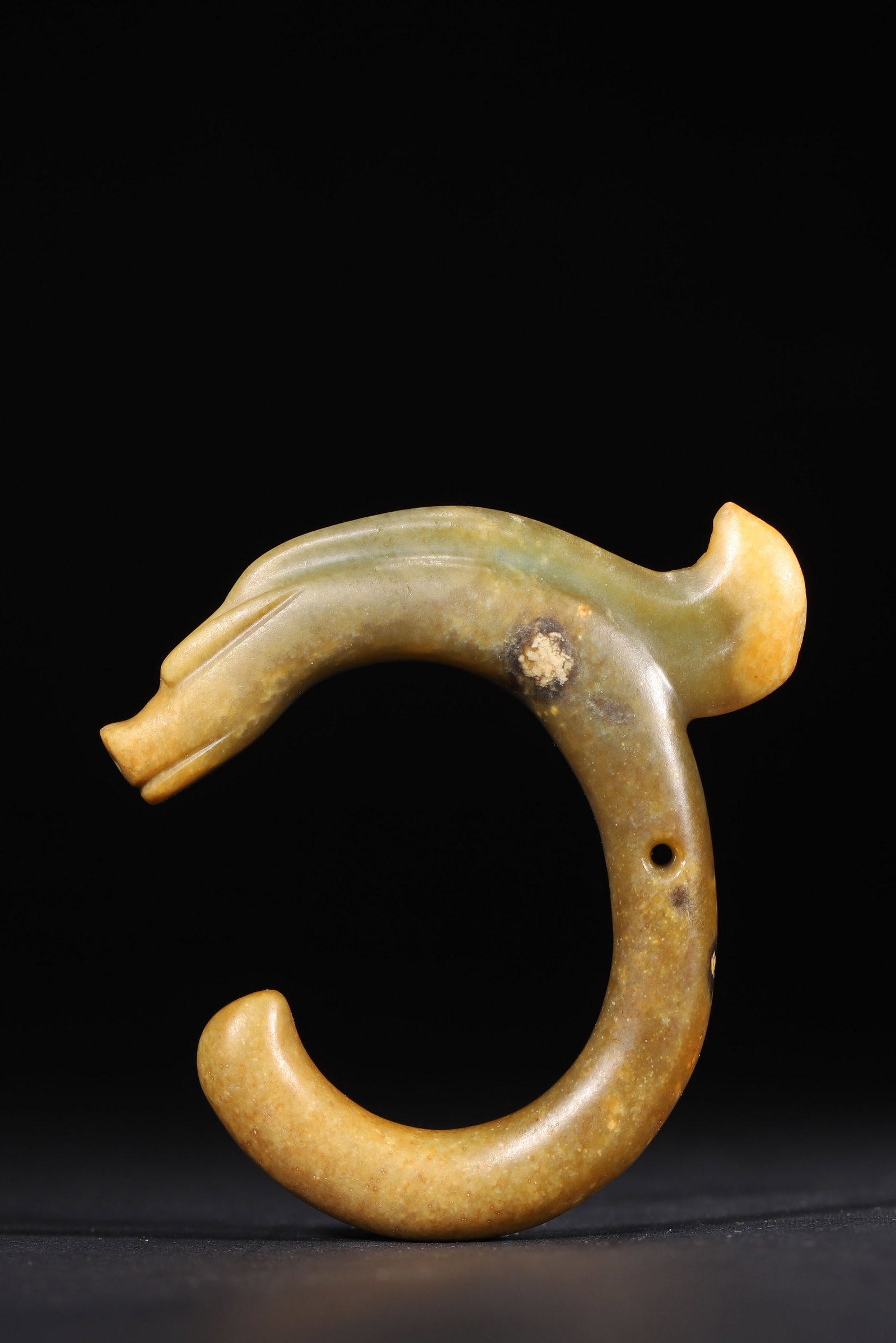 A C-Shaped Jade Dragon, Prehistoric Culture: 7.0cm x 7.0cm,42.0g (2.76in x 2.76in,WT 0.0926lb)A C-shaped jade dragon, elegantly coiled with archaic simplicity. Naturally patinated, it embodies the ritual symbolism of prehistoric jade culture.
