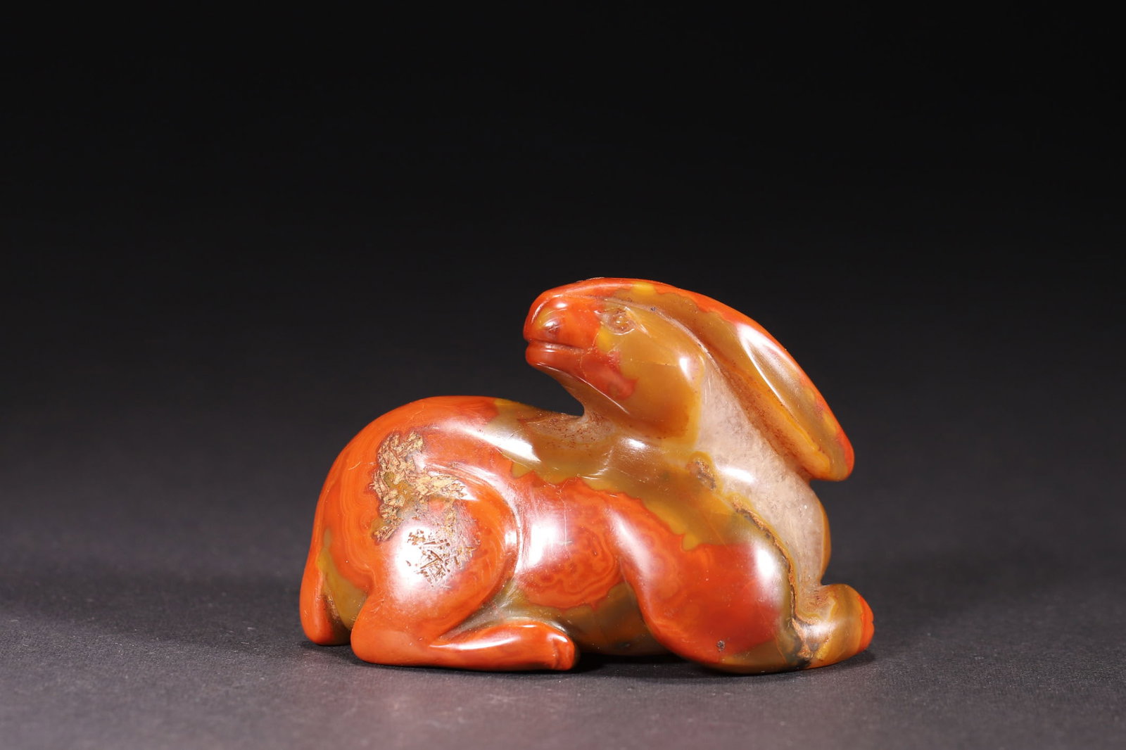 A Red Agate Rabbit Ornament (Han Dynasty): Length 6.5cm (2.56in), Width 4.3cm (1.69in), Height 5.0cm (1.97in), Weight 147.0g (0.32lb)This red agate ornament, carved in the round into a crouching rabbit form, features the typical vigorous and c