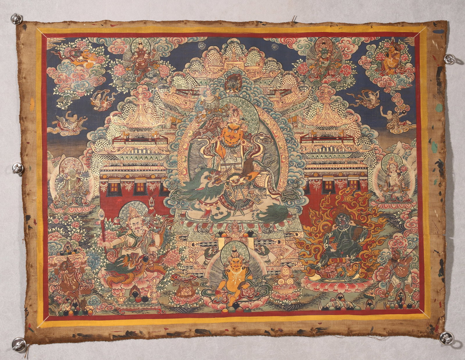 A Vaisravana Thangka, Qing Dynasty: L 82cm (32.28 in); W 60cm (23.62 in)This Qing Dynasty thangka depicts Vaisravana (Yellow Jambhala) riding a lion, surrounded by his pure land and other protectors. With bright colors, fine lines, and 