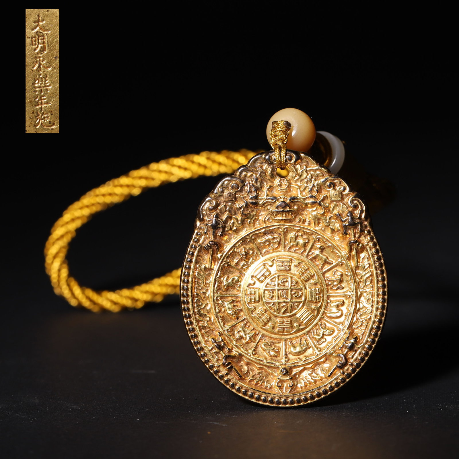 A Gilt Bronze Nine Palaces and Eight Trigrams Amulet, Yongle Period, Ming Dynasty: L 5.3cm (2.09 in); W 4.3cm (1.69 in); Wt 53g (0.12 lb)A gilt bronze amulet carved with Tibetan-style nine palaces, eight trigrams, zodiac animals and eight auspicious symbols on the obverse, with a "M