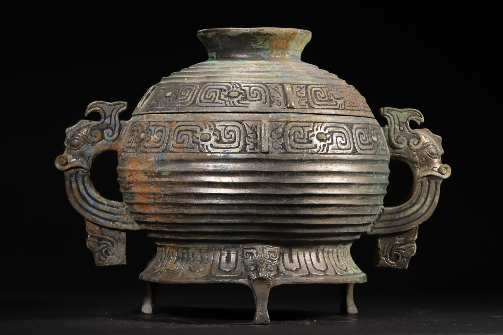 A Bronze Tripod Gui Vessel with Beast-Handles and Ribbed Pattern, Western Zhou Dynasty: 3447.0 g (7.6 lb) | 33.0 x 20.0 x 21.0 cm (12.99 x 7.87 x 8.27 in)This Western Zhou Dynasty bronze gui features a robust form with two powerful beast-head handles. Its body is elaborately decorated wi