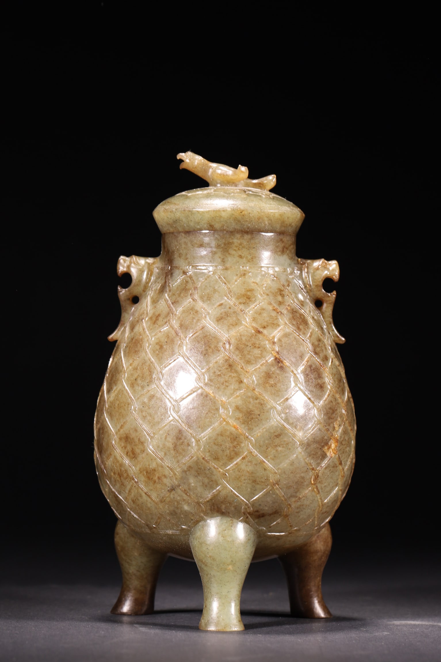 A Hetian Jade Tripod Censer with Bird Finial and Net Pattern, Han Dynasty: Diameter 9.0cm (3.54in), Height 18.0cm (7.09in), Weight 541.0g (1.19lb)This Han Dynasty Hetian jade tripod censer features a bird finial, beast-head handles, and net pattern. The natural patina and ex