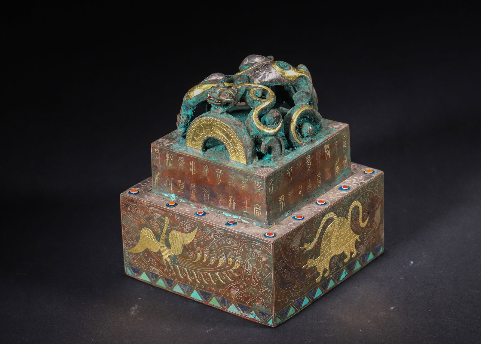 A Bronze Square Seal with Gold/Silver Inlay and Turquoise, Han Dynasty: Length 10.0cm (3.94in), Width 10.0cm (3.94in), Height 11.5cm (4.53in), Weight 2289.0g (5.05lb)This Han Dynasty square seal is cast in bronze, adorned with gold and silver inlay and turquoise. It featu
