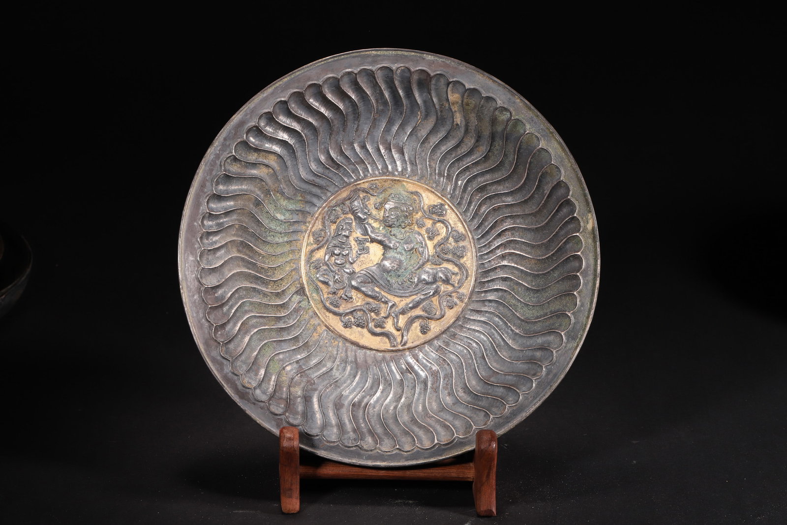 A Tang Dynasty Gilt Silver Plate with Musician Motif: Diameter 21.0cm (8.27in), Weight 177.0g (0.39lb)A Tang Dynasty gilt silver plate, crafted with silver and partially gilded. The center features a vivid musician scene, surrounded by radiating water pa
