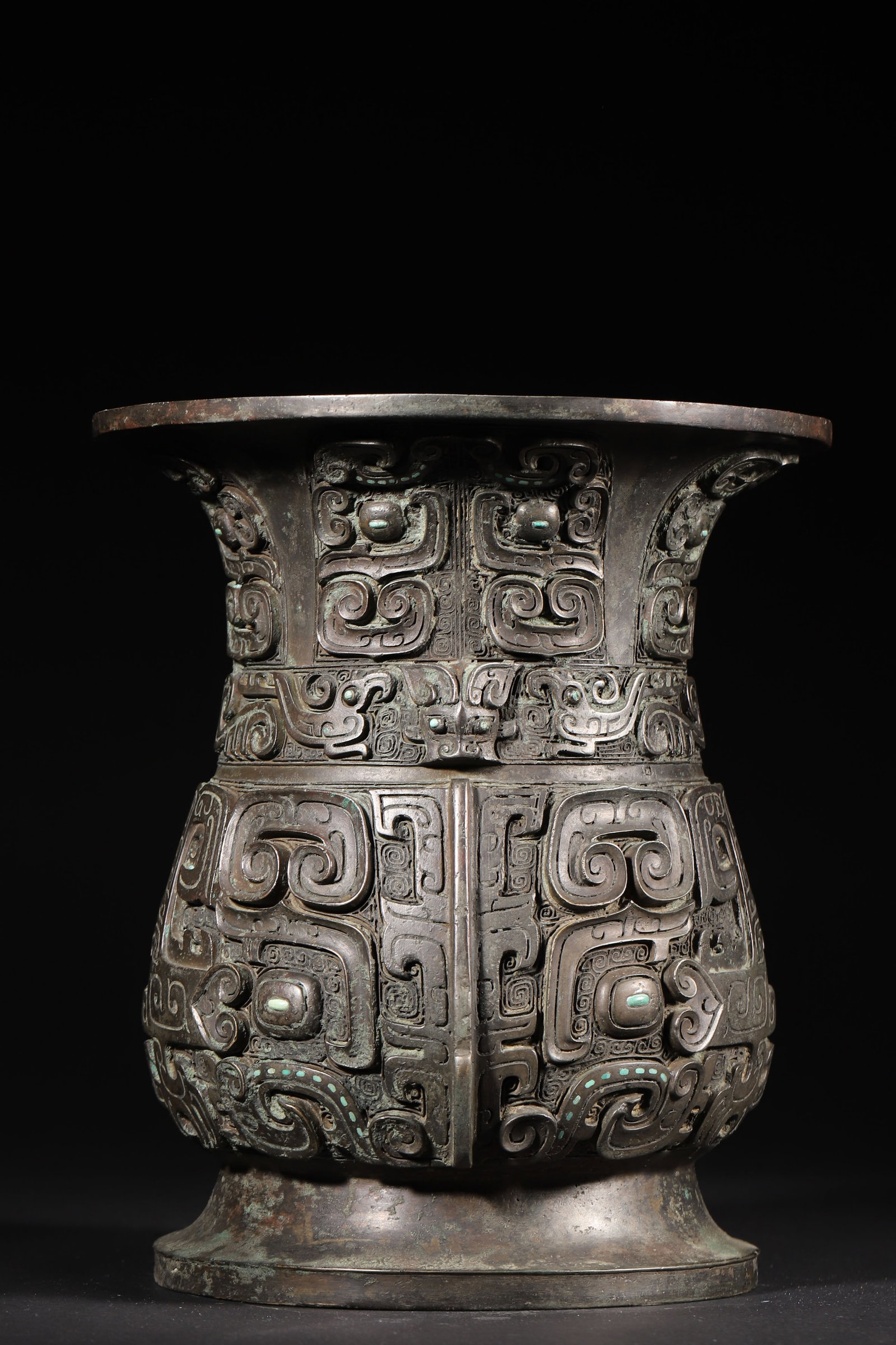 A Bronze Zun Vessel with Animal Mask Pattern, Late Shang Dynasty: 5227.0 g (11.52 lb) | D 21.0 cm (D 8.27 in)This Late Shang Dynasty bronze Zun, boasting a noble shape with a flared mouth, contracted neck, hanging belly, and high footring, is a fine ritual vessel. I