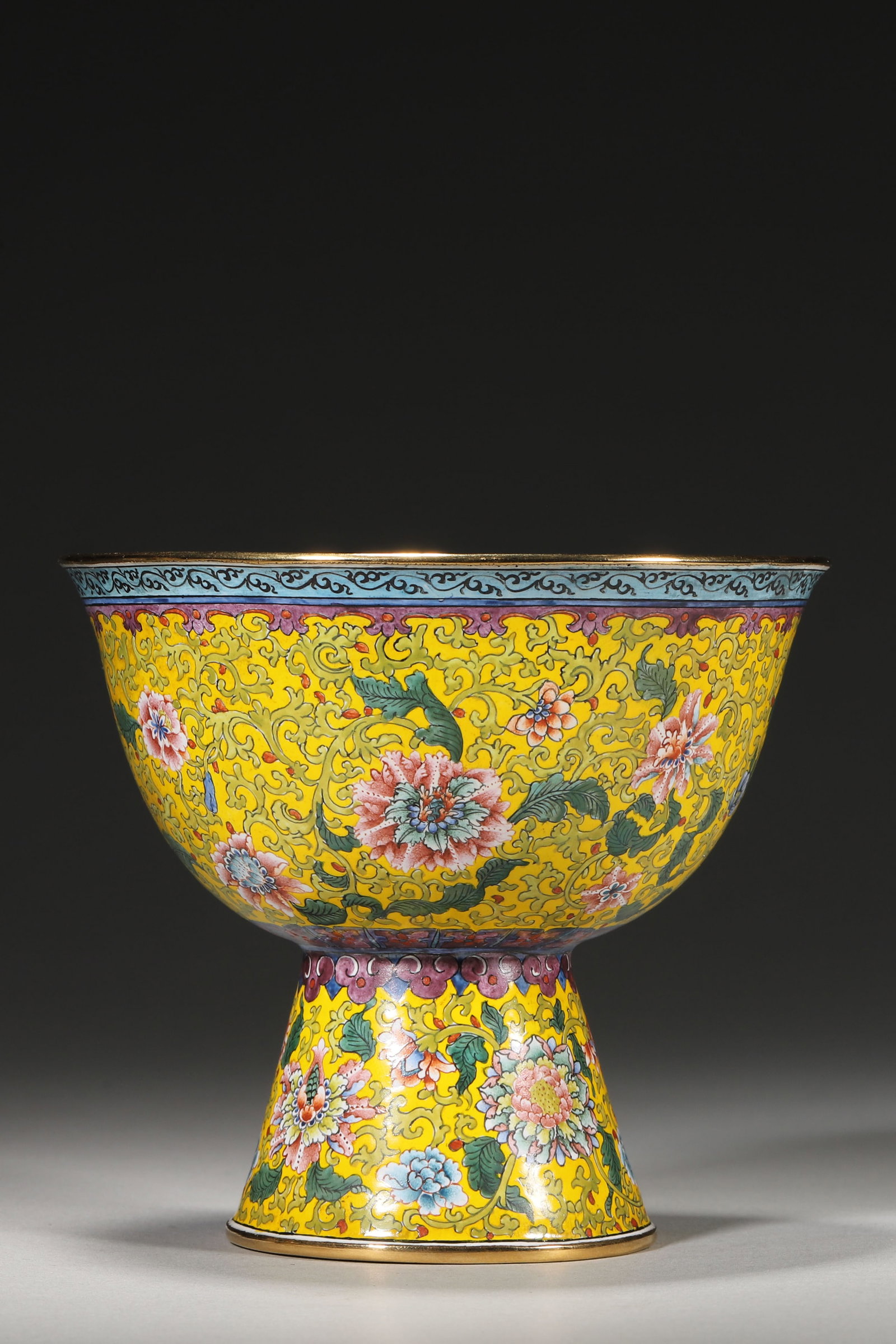 An Enameled Copper Stem Cup with Floral Scrolls, Qianlong Period: 11.0cm x 10.0cm,263.0g (4.33in x 3.94in,WT 0.5798lb)This enameled copper stem cup features floral scrolls on a yellow ground, with gilt rims, turquoise interior and a Qianlong mark. It embodies imperi