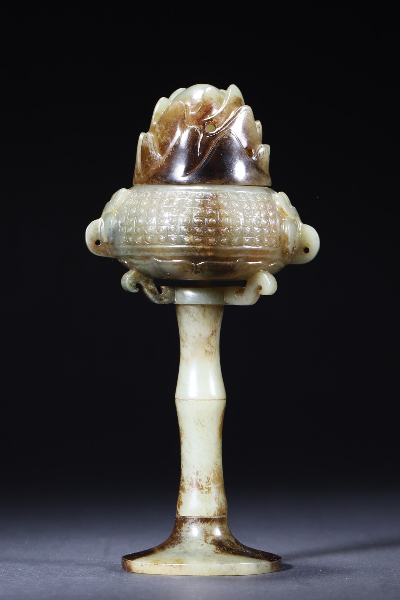 A Hetian Jade Stemmed Boshan Censer, Han Dynasty: Width 9.0cm (3.54in), Height 20.0cm (7.87in), Weight 348.0g (0.77lb)This Han Dynasty Hetian jade stemmed Boshan censer is composed of three detachable parts. The mountain-shaped lid has openwork holes