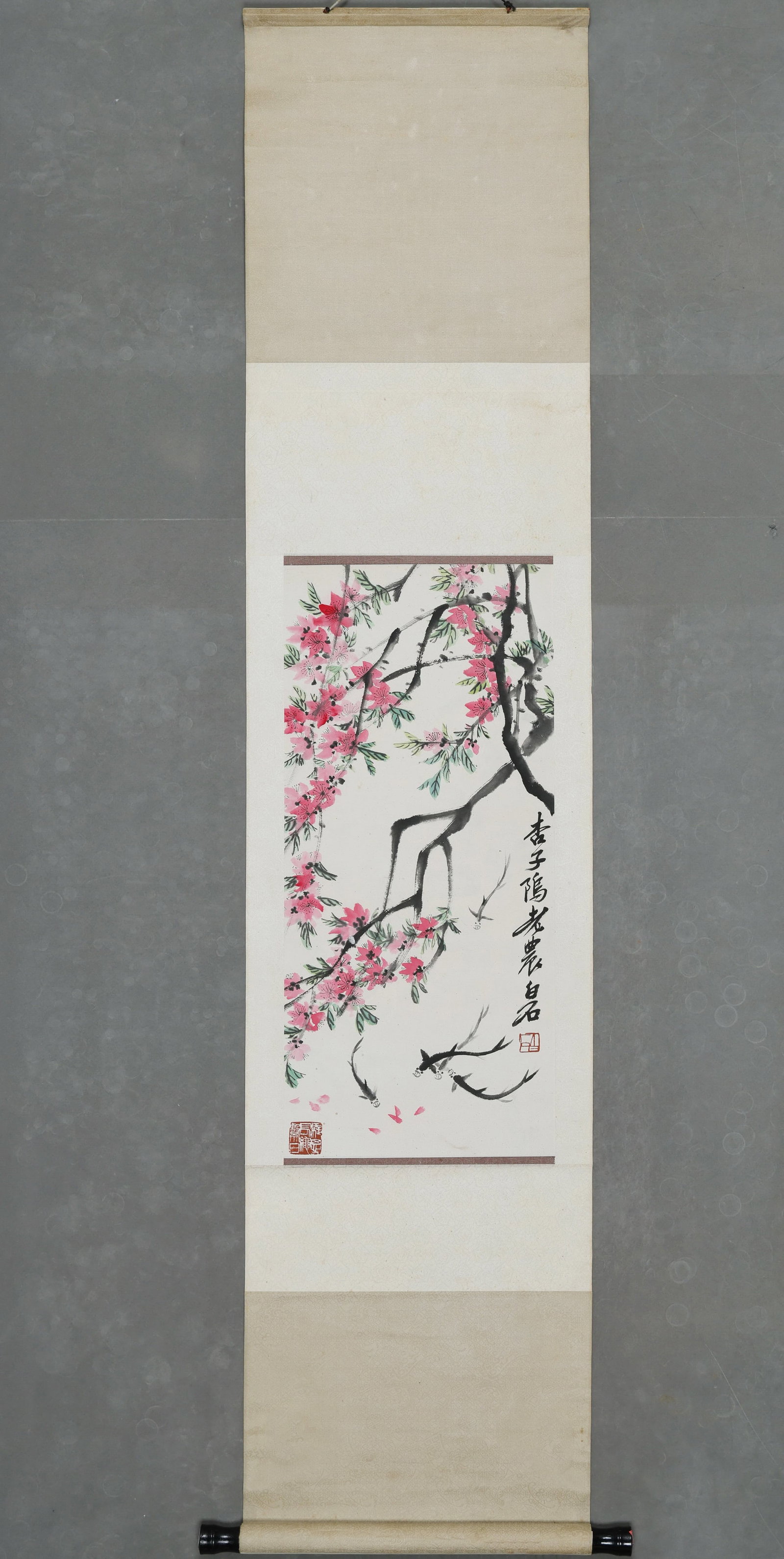An Ink and Color Painting "Peach Blossoms and Fish" by Qi Baishi, Hanging Scroll: Painting Core SizeL 65cm (25.59 in); W 30cm (11.81 in)This hanging scroll, Peach Blossoms and Fish by Qi Baishi, depicts spring scenery with vibrant peach blossoms and swimming fish in freehand brushw