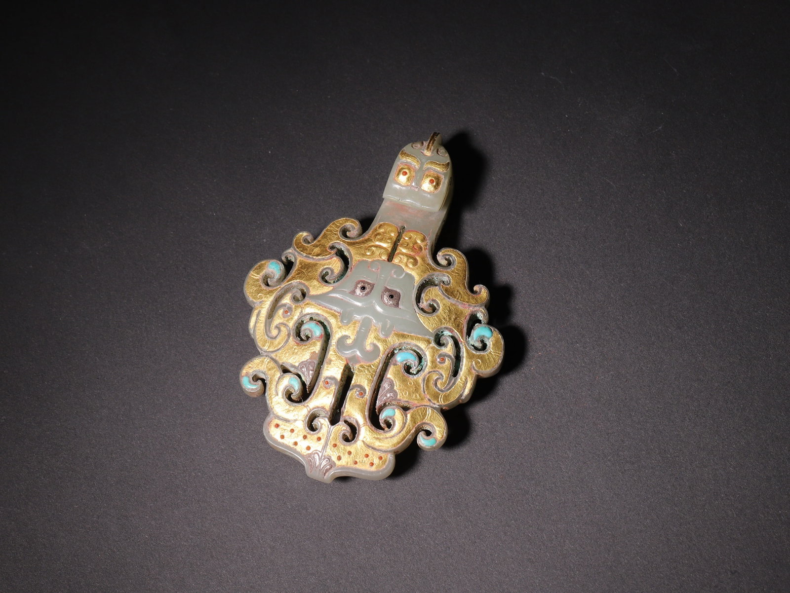 A Hetian Jade Gold and Silver Inlaid Precious-Stone-Embellished Belt Hook, Han Dynasty: L 10.5cm (4.13 in); W 7.0cm (2.76 in); Wt 87.0g (0.19 lb)A Han Dynasty Hetian jade belt hook with fine gold and silver inlay and precious stone embellishments. The jade is smooth and lustrous, showcas