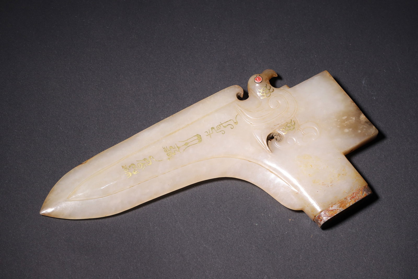 A Gold-Decorated and Gem-Embedded Jade Ge Dagger-Axe with Phoenix Motif, Warring States Period: Length 16.5cm (6.5 in); Width 8.5cm (3.35 in); Weight 189.0g (0.42 lb)This Warring States Period jade ge dagger-axe, carved from fine Hetian white jade, features a slender blade with gold-decorated in