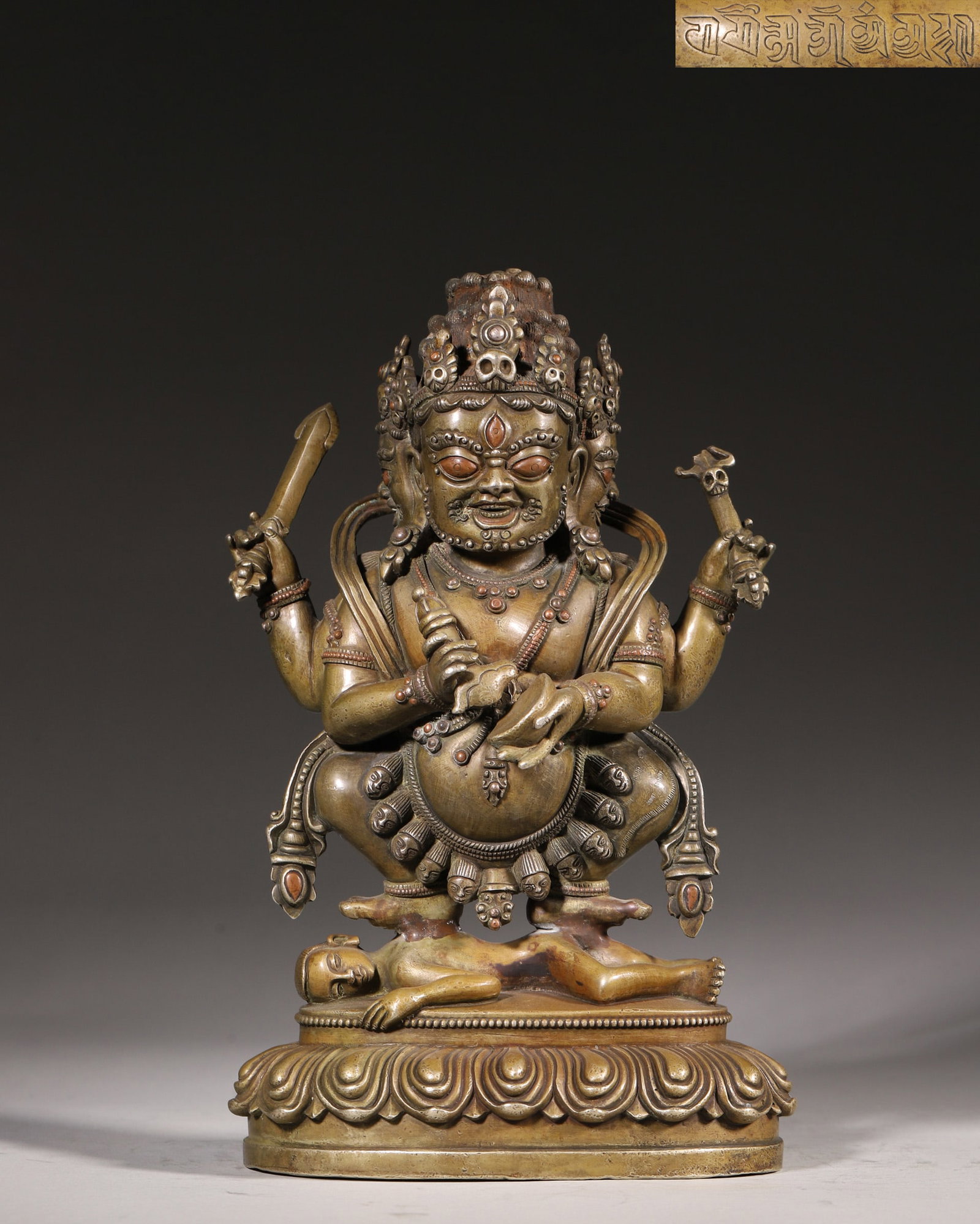 A Copper Statue of Three-Faced Four-Armed Mahakala with Silver and Copper Inlay, Qing Dynasty: H 23cm (9.06 in); L 15cm (5.91 in); W 8.5cm (3.35 in); Wt 2570g (5.67 lb)This Qing Dynasty copper statue depicts the three-faced four-armed Mahakala, adorned with silver and copper inlay. Standing in 