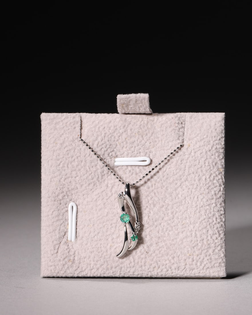 An 18K White Gold Twisted Two-Stone Emerald Pendant Necklace with Diamond Accents: L 22.0cm (8.66 in); Wt 3.0g (0.01 lb)Crafted in polished 18K white gold with curved twisted shank, this pendant is set with two vivid green round emeralds and accent diamonds. Matched with fine box ch