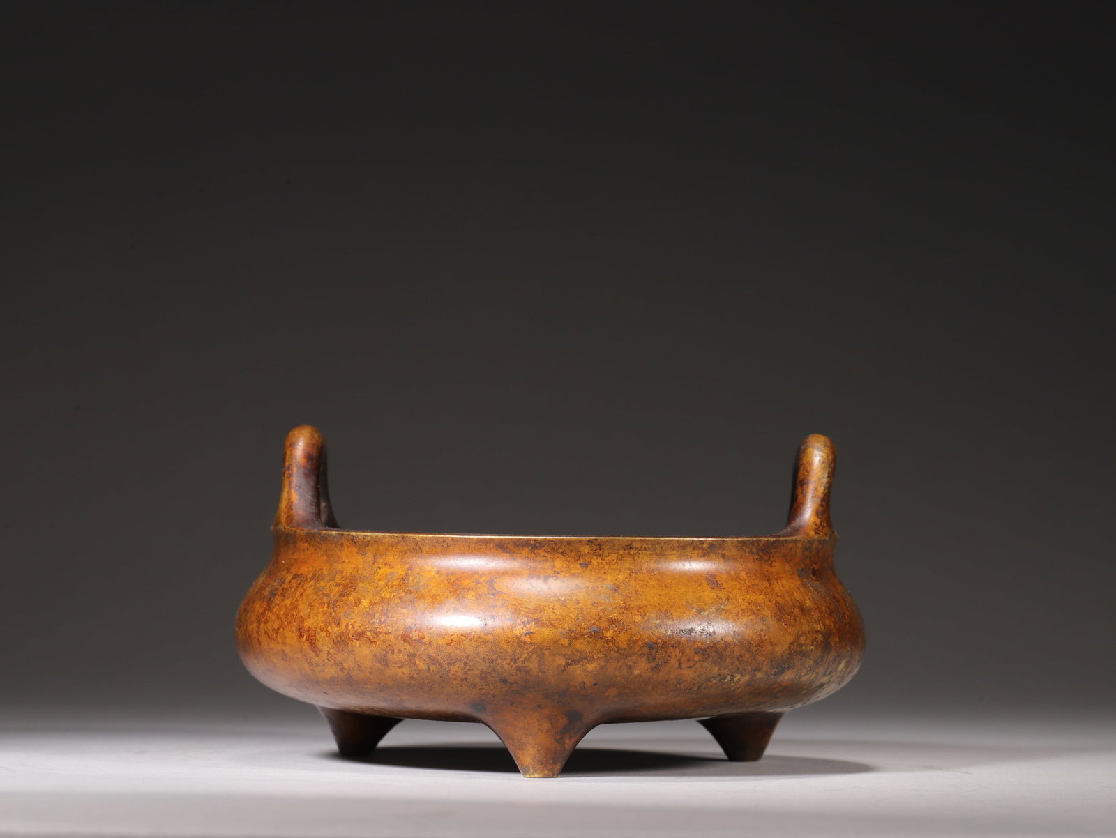A Bronze Tripod Censer with Upright Handles, Qing Dynasty: D 15.0cm (5.91 in); H 8.0cm (3.15 in); Wt 1194.0g (2.63 lb)A bronze tripod censer with upright handles, Qing Dynasty. It is crafted from fine solid bronze with mellow and elegant patina. Featuring cla
