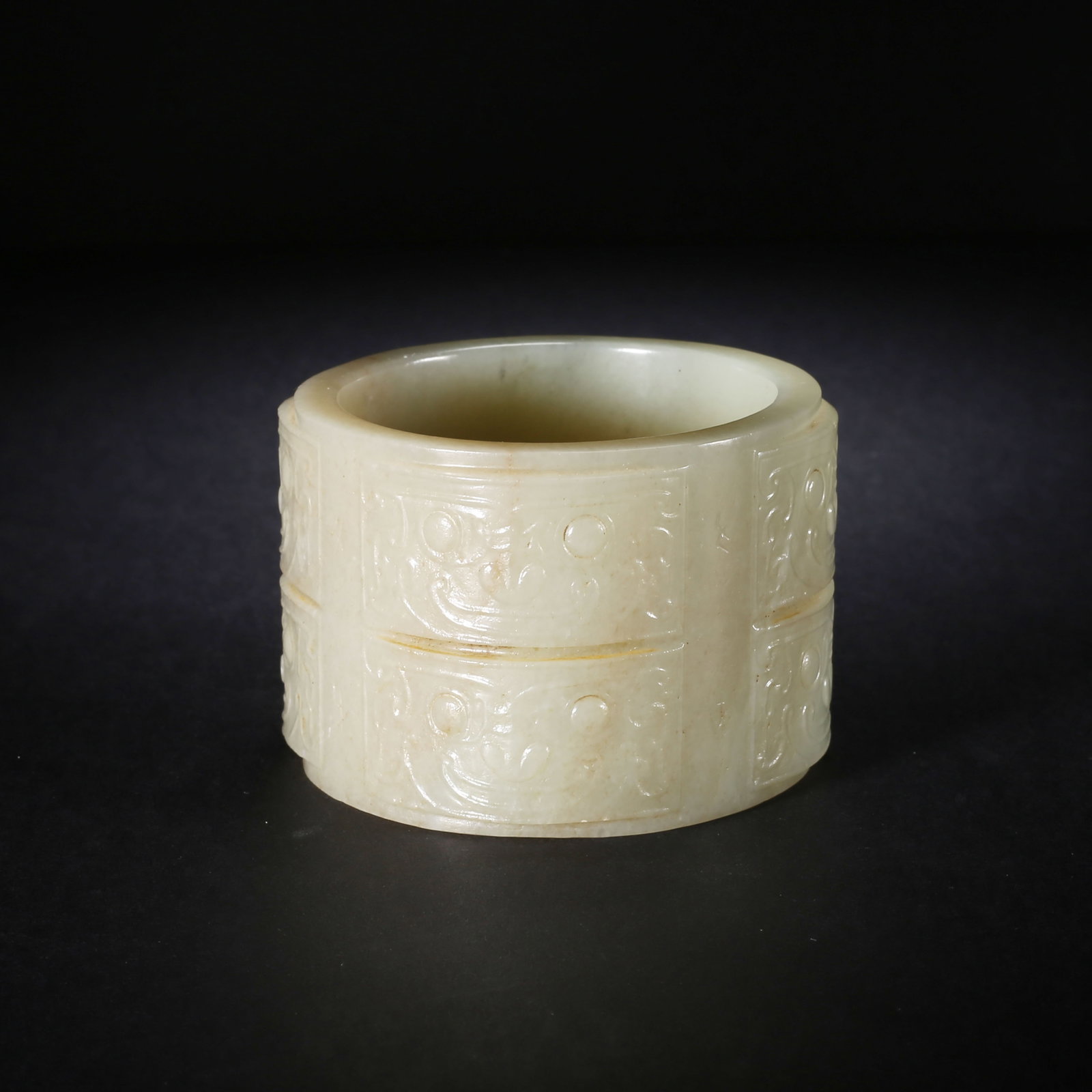 A Hetian Jade Cylindrical Band with Beast Mask Pattern Shang Zhou Dynasty: L 7.13cm (2.81 in); W 7.04cm (2.77 in); H 5.12cm (2.02 in); Wt 216.6g (0.48 lb)This Shang Zhou cylindrical band of creamy Hetian jade is decorated with divided archaic beast masks and faint aged yello