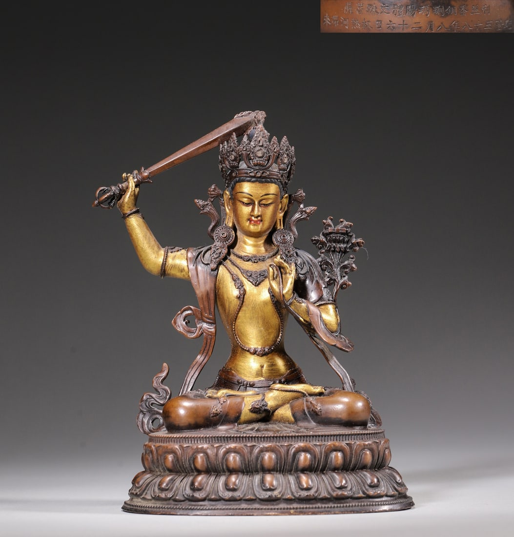 A Palace-Made Partially Gilt Bronze Statue of Manjushri, Qianlong Period, Qing Dynasty: L 11.0cm (4.33 in); W 8.5cm (3.35 in); H 16.0cm (6.3 in); Wt 550.0g (1.21 lb)A palace-made partially gilt bronze statue of Manjushri from the Qianlong period. The deity sits on a lotus throne, holding