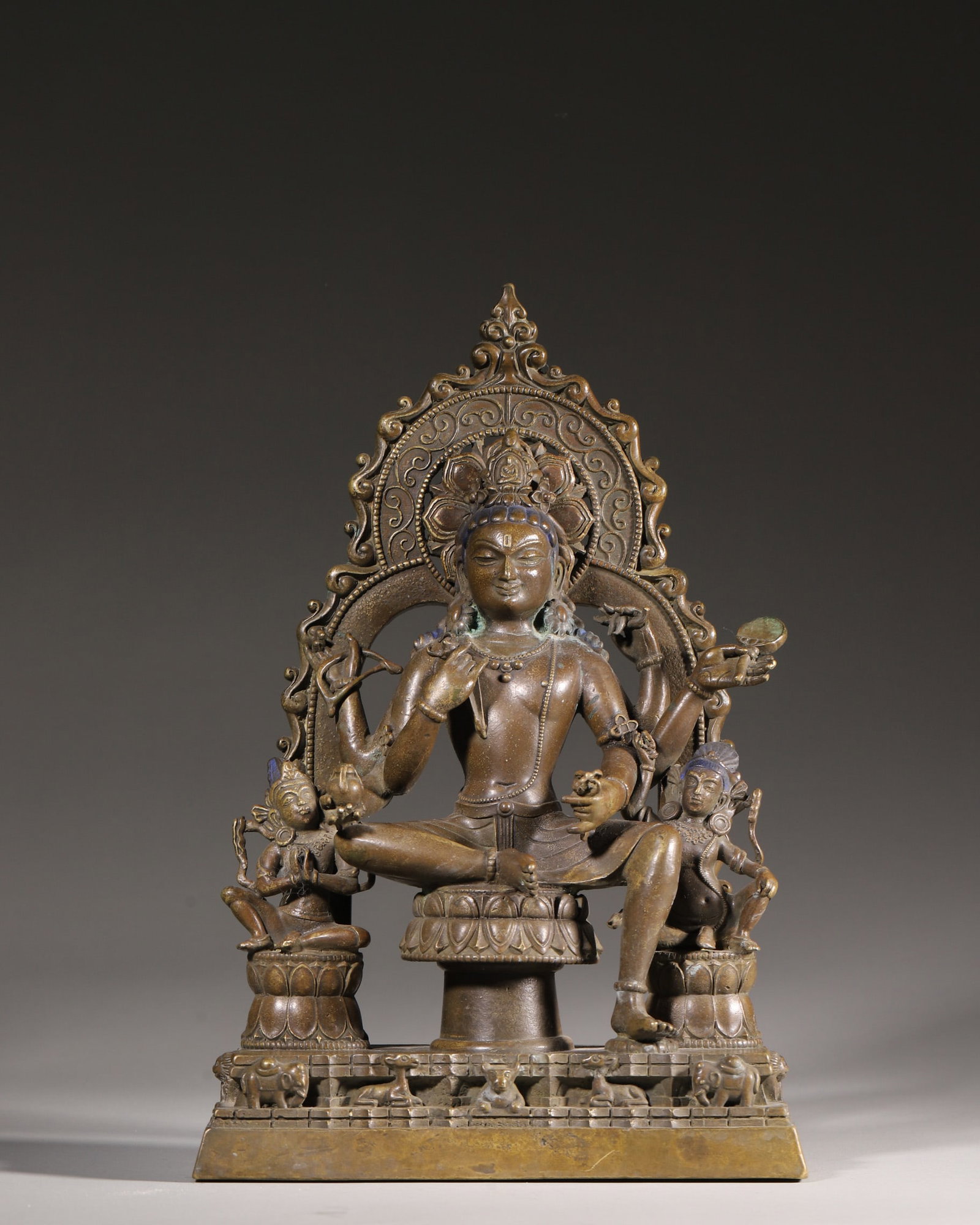 A Bronze Four-Armed Avalokitesvara Group Statue, Qing Dynasty: H 28cm (11.02 in); L 18cm (7.09 in); W 9cm (3.54 in); Wt 3.48kg (7.67 lb)This Qing Dynasty bronze group statue features the four-armed Avalokitesvara seated on a lotus pedestal with attendants. Adorne