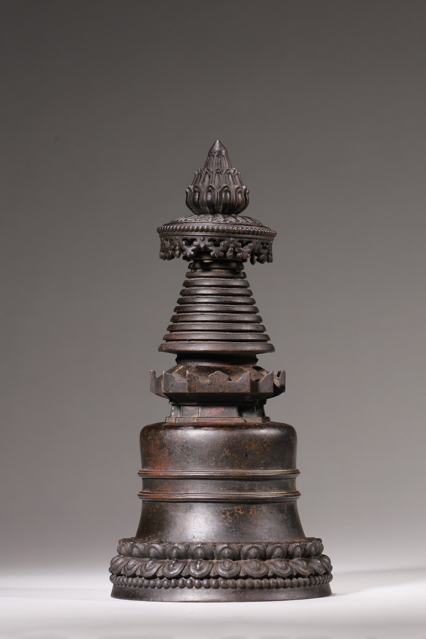A Copper Kadam Stupa, Qing Dynasty: H 22cm (8.66 in); D 10cm (3.94 in); Wt 1227g (2.71 lb)This is a copper Kadam Stupa of the Qing Dynasty, cast in fine copper with a mellow patina. Composed of a lotus-petal base, bell-shaped dome, thir