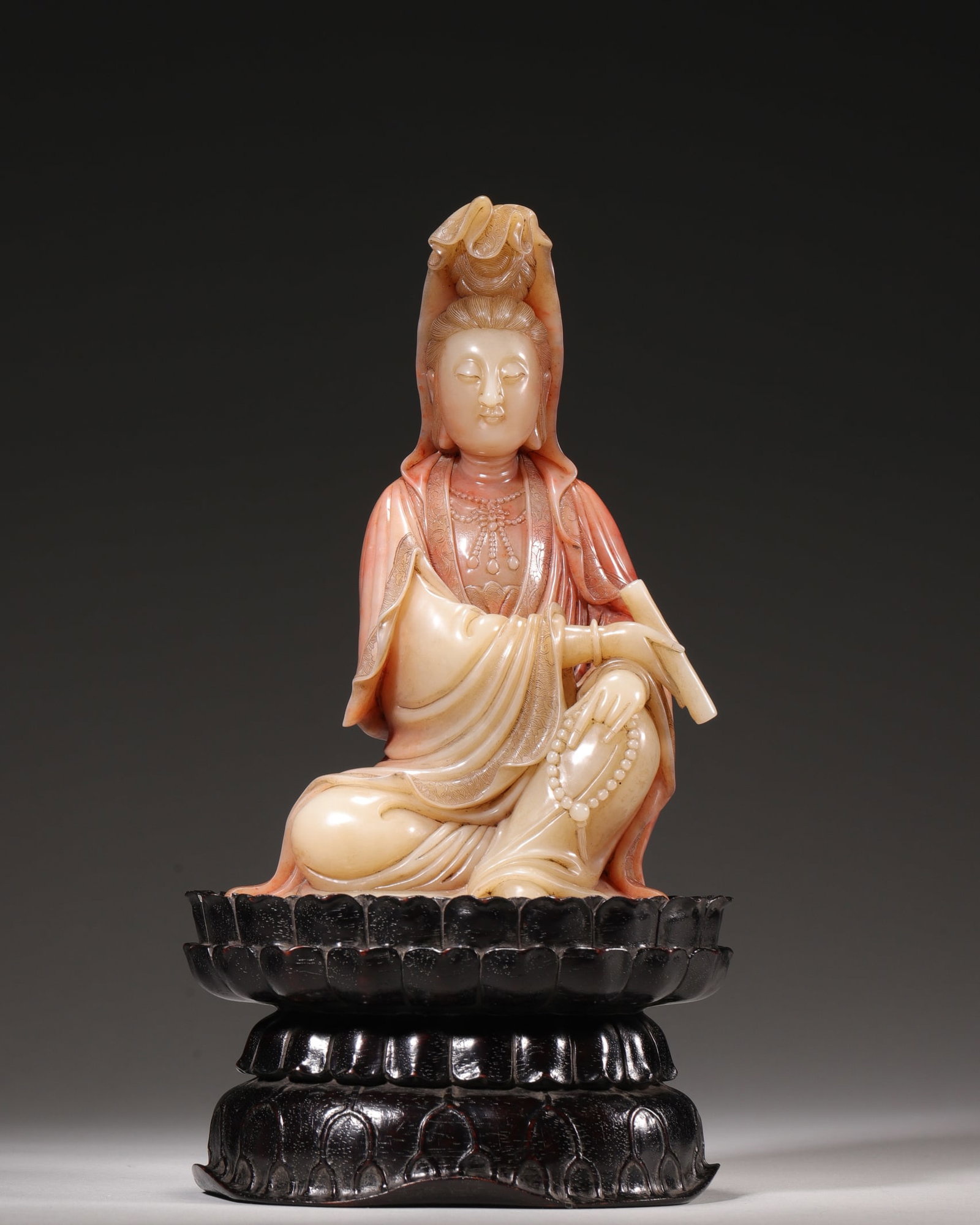 A Qing Dynasty Shoushan Furong Stone Carved Guanyin Statue with Scroll and Zitan Lotus Base: L 11.0cm (4.33 in); W 8.0cm (3.15 in); H 19.0cm (7.48 in); Wt 1131.0g (2.49 lb)This is a Qing Dynasty Shoushan Furong stone Guanyin statue, carved from a whole piece of high-quality Furong stone with 