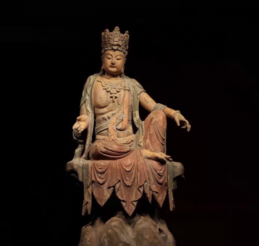 A Painted Figure of Free Guanyin,Song Dynasty: Nanmu wood. Height: 103 cm, Width: 55 cm, Depth: 42 cm. The statue has a benevolent facial expression and elegant posture. It sits leisurely on a rockery in a free and relaxed manner, ideal for enshri