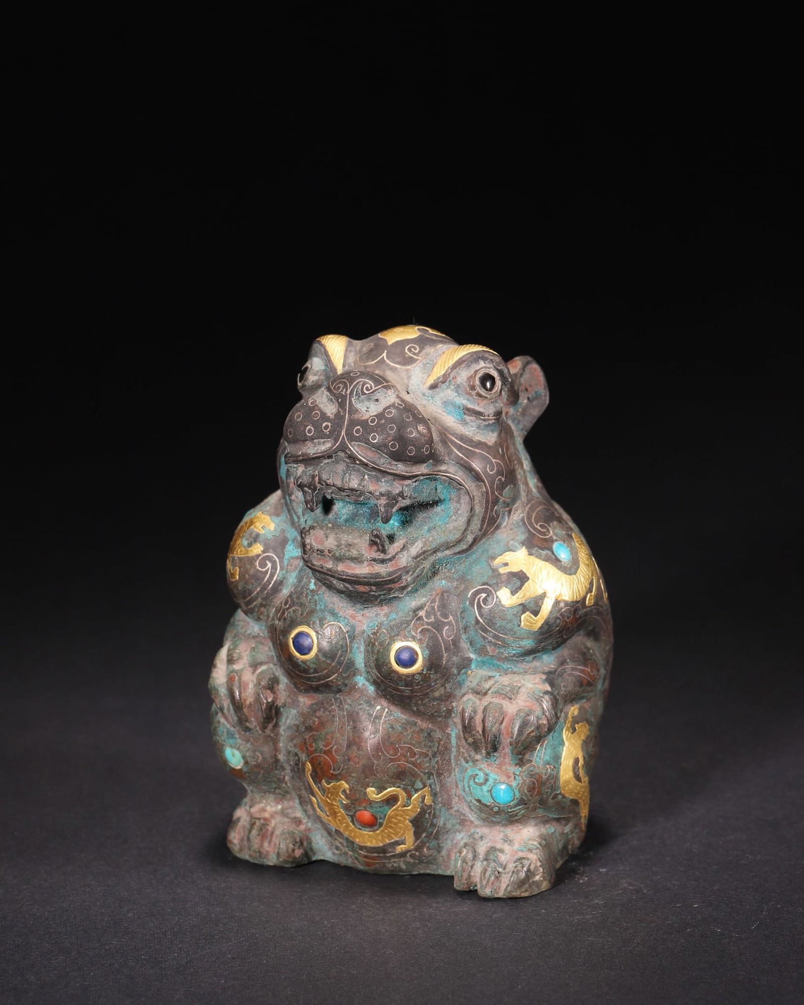 A Bronze Gold and Silver Inlaid Bear Ornament with Gemstone Inlay, Han Dynasty: L 7.0cm (2.76 in); W 6.5cm (2.56 in); H 10.0cm (3.94 in); Wt 473.0g (1.04 lb)A Han Dynasty bronze bear ornament, exquisitely inlaid with gold, silver, turquoise, and lapis lazuli. Features vivid bear 