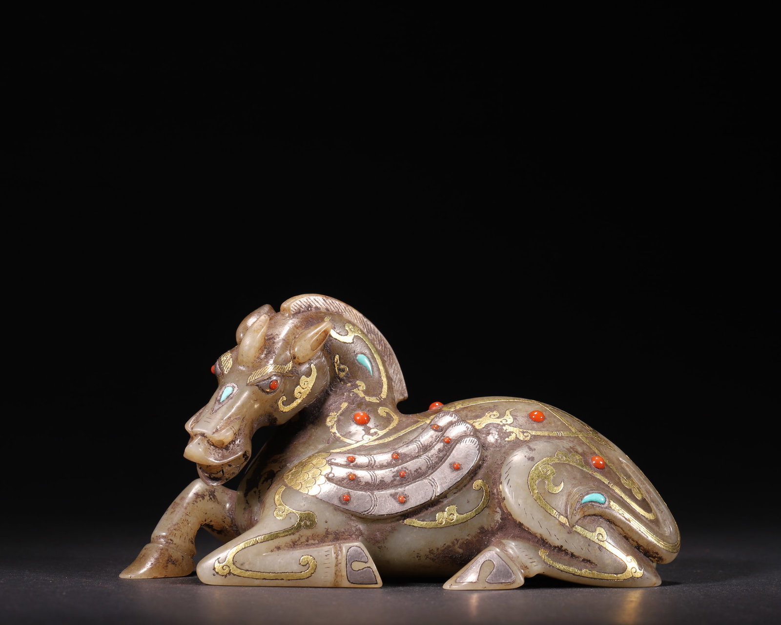 A Hetian Jade Winged Horse Ornament with Gold, Silver, Turquoise and Coral Inlays, Han Dynasty: L 14.0cm (5.51 in); W 6.5cm (2.56 in); H 7.5cm (2.95 in); Wt 570.0g (1.26 lb)A Han Dynasty Hetian jade winged horse ornament with fine gold and silver inlays, embellished with turquoise and coral. The