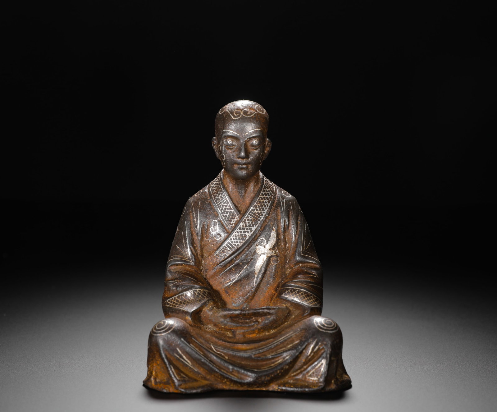 HAN DYNASTY IRON INLAID SILVER SEATED ARHAT: H:12cm(4.72in)W:8.5cm(3.35in)Weight:430g(0.95lb)Dating from the early spread of Buddhism in China, this statue reflects the integration of Buddhist art with native metalwork, embodying devotion and se