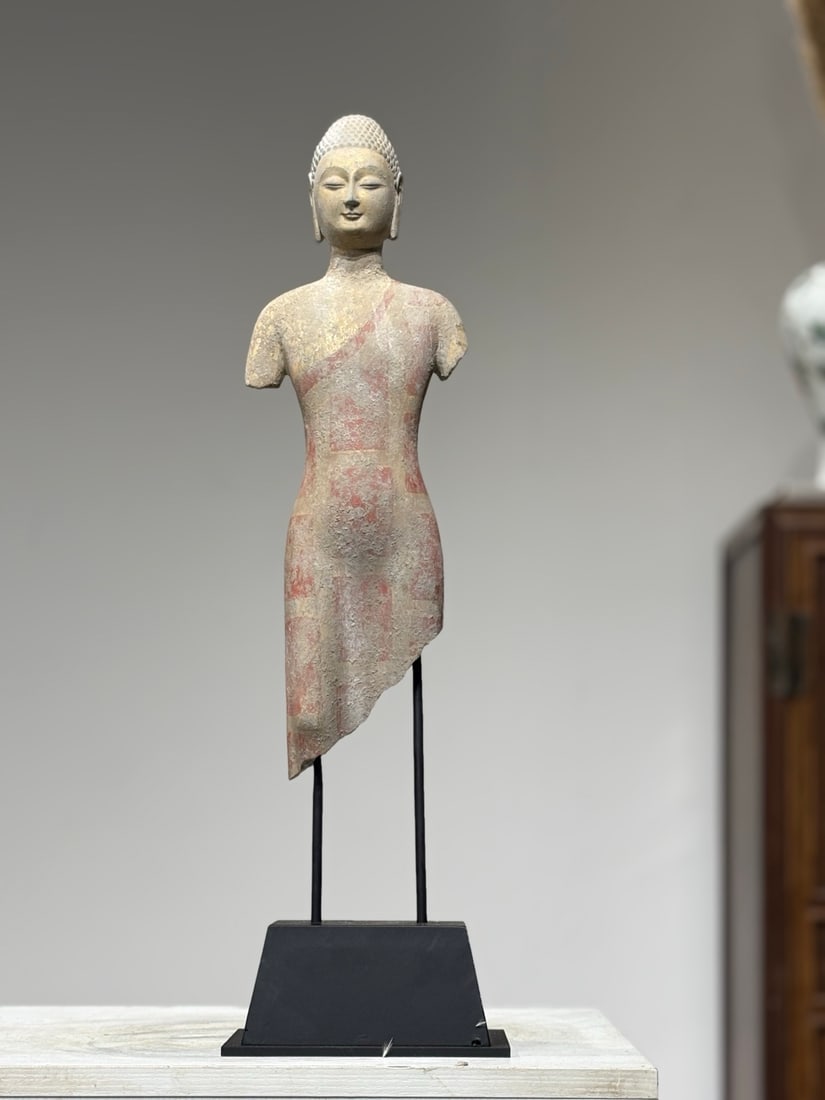 A PAINTED GILDED STONE FRAGMENTARY STANDING SHAKYAMUNI BUDDHA, NORTHERN QI DYNASTY: TotalHeight53cm BuddhaHeight38cm,Northern Qi stone carving fragment of standing Shakyamuni Buddha, mounted on modern trapezoidal metal display stand. The cranial protuberance is covered with dense bea