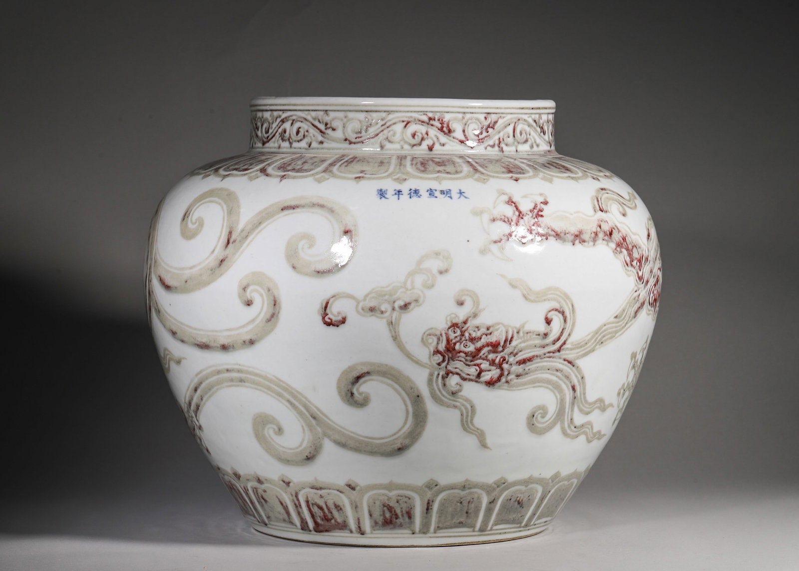 A UNDERGLAZE RED PORCELAIN JAR WITH CHI DRAGON MOTIF, XUANDE PERIOD, MING DYNASTY: H 34cm (13.39 in); D 43cm (16.93 in); Cal. 24.5cm (9.65 in),Ming Xuande official underglaze red jar with sand base. Scroll grass on rim and lotus panels on shoulder, inscribed six-character blue mark 
