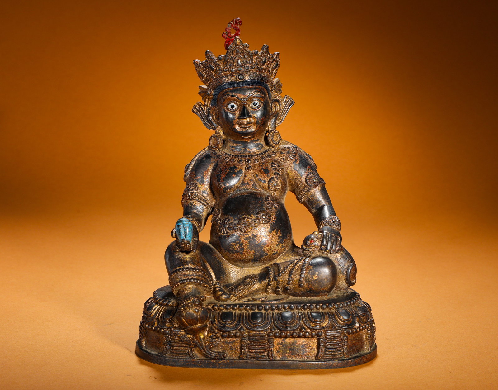 A GILDED BRONZE STATUE OF THE GOD OF WEALTH FROM THE QING DYNASTY: Height:26cm(10.24in) Width:19cm(7.48in) Weight:2420g(5.33lb)Gilt bronze statue of Yellow Jambhala wealth deity of Tibetan Buddhism. Bronze body with worn partial gilding, five-leaf crown embedded with
